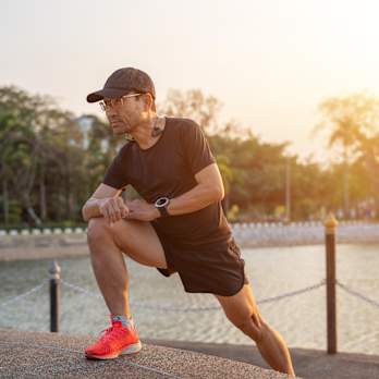 Man stretching outside in morning sunlight as part of marathon strength training