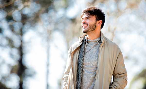 A smiling man going on a walk outside, which is a great self-care idea.