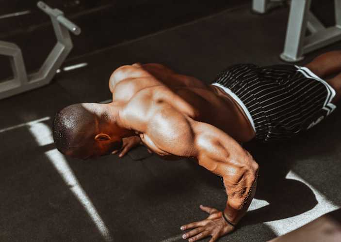 Man doing bodyweight back exercises in a gym.