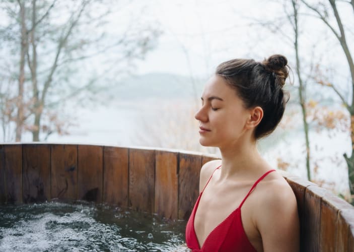 A woman closing her eyes while taking a cold plunge before or after a workout.