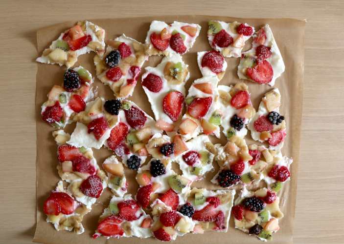 A tray of vegan Greek yogurt bark with various fruits in it like strawberry, banana, kiwi, blackberries, and raspberries. It's a high-protein vegan snack.