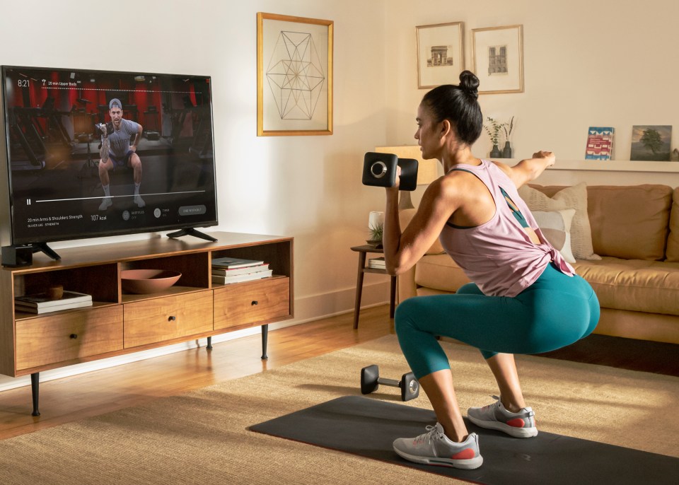 Woman using hand weights for a home workout using the Peloton home app.