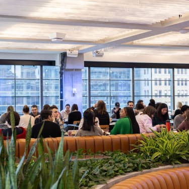 Peloton team members engaging in conversation and eating meals at tables in an office dining area.