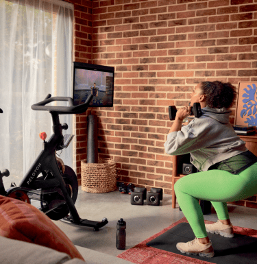 Woman using Peloton bike plus in her home