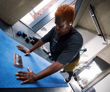 A man holding plank position on a workout mat while watching a Peloton class on his mobile phone.