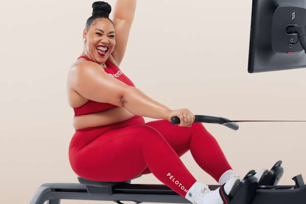 Cheerful instructor cheering while sitting on a Peloton Row machine.