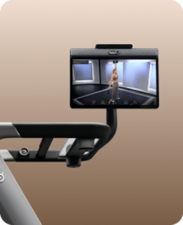 Close-up of a Peloton Tread's handrail and swivel screen showing a fitness instructor leading a strength workout.