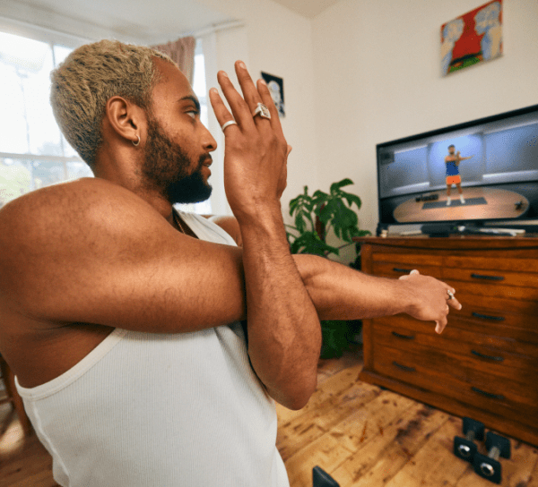 man stretching watching Peloton instructor