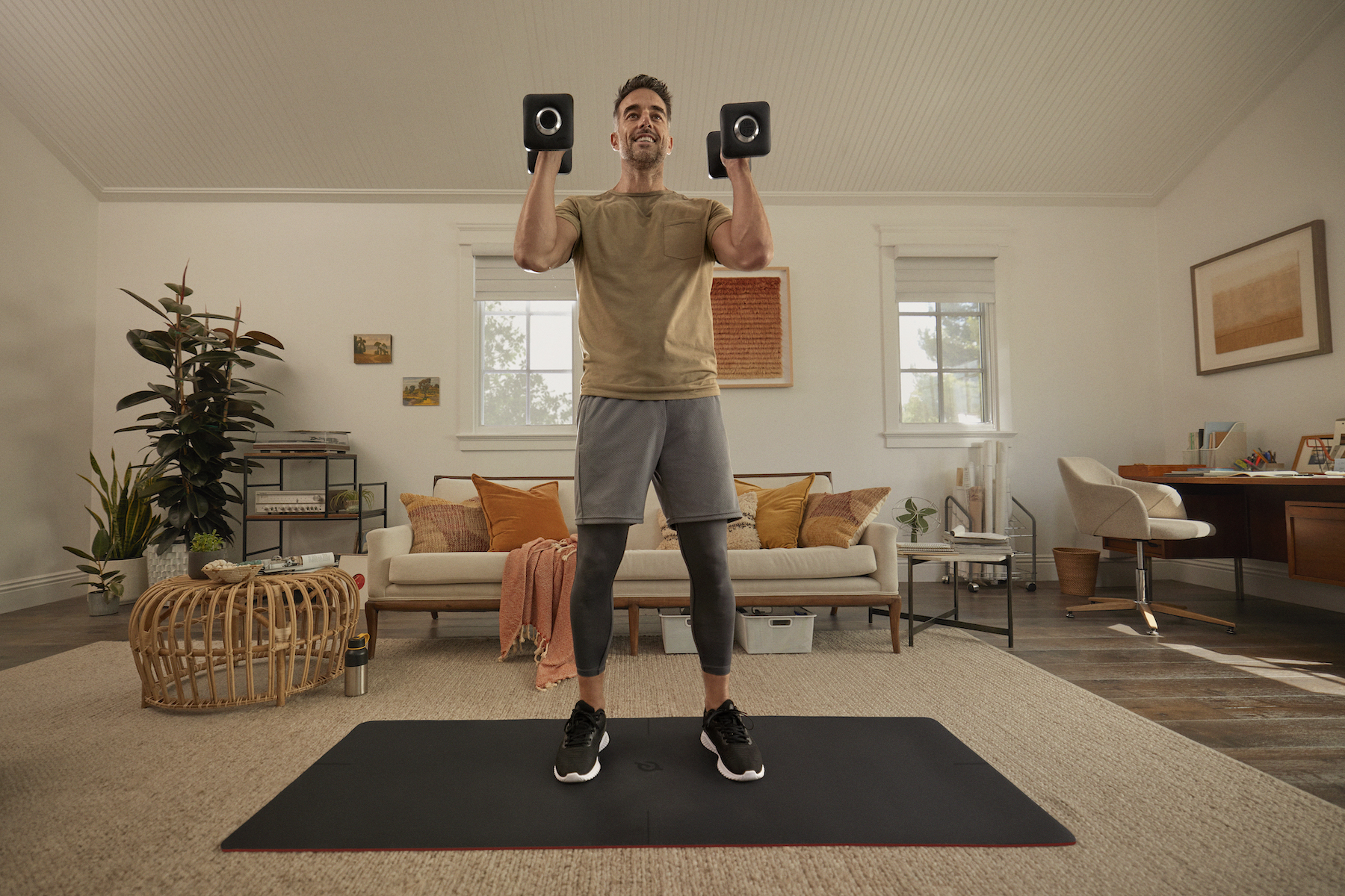Man holds weights during a workout at home