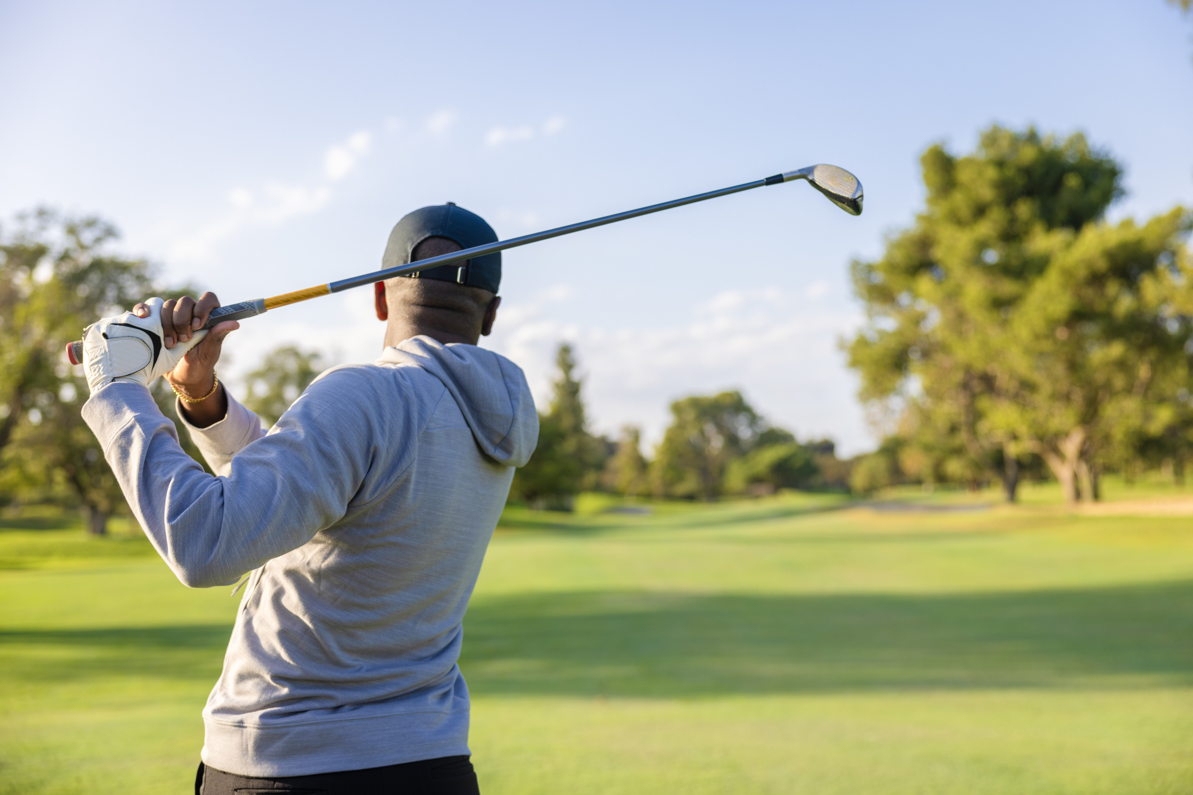 Man swinging golf club on course