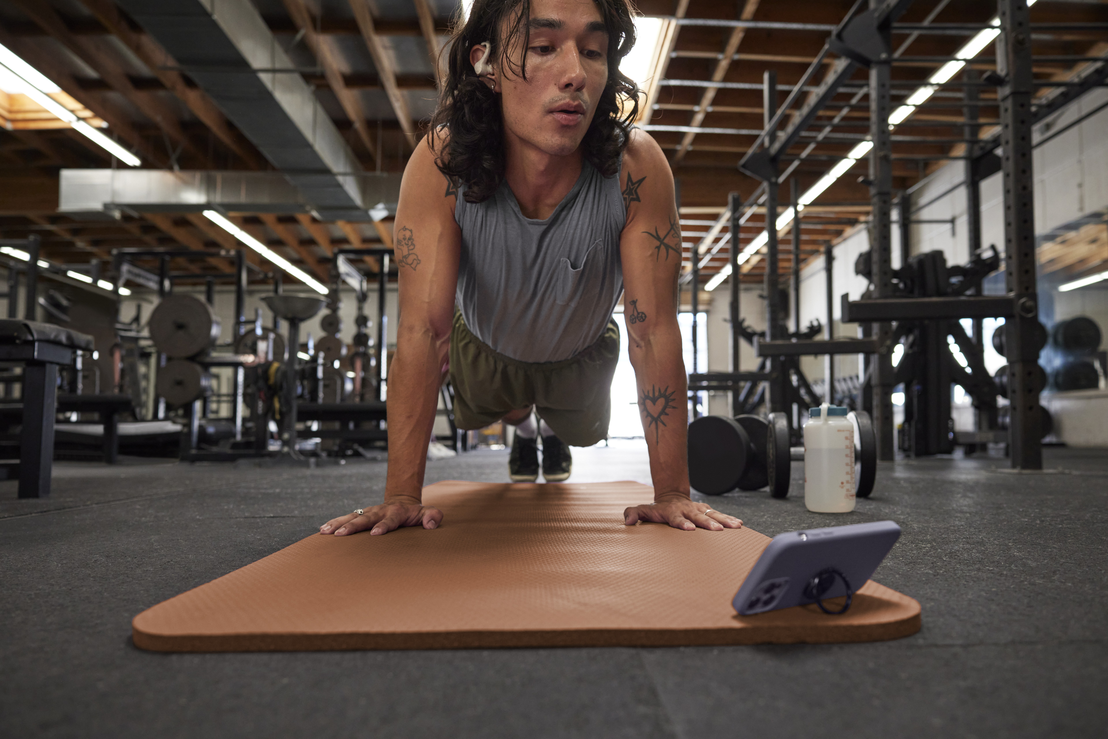 Man does a plan exercise while looking at phone