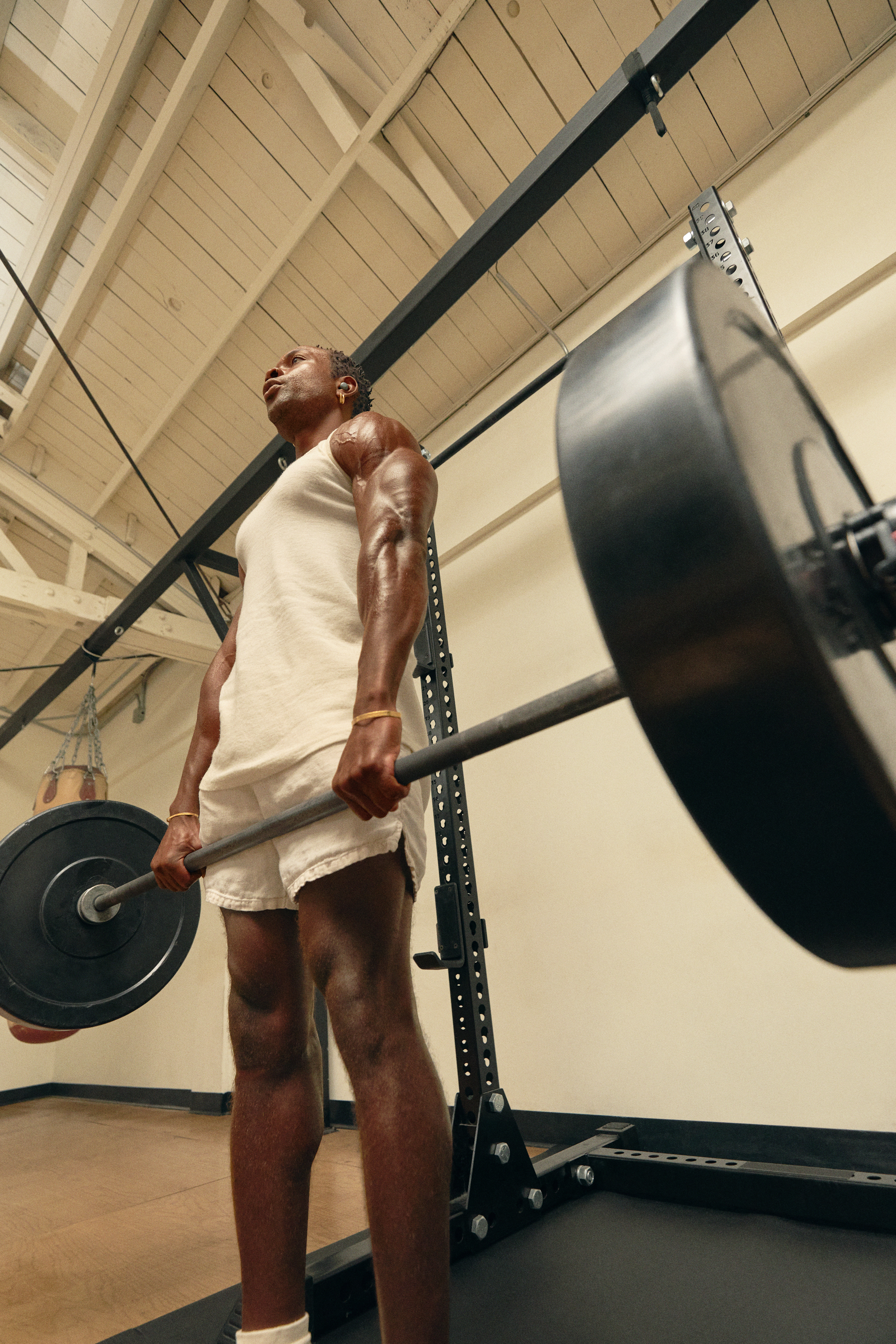 Muscular young man doing a barbell deadlift in front of a squat rack in the gym