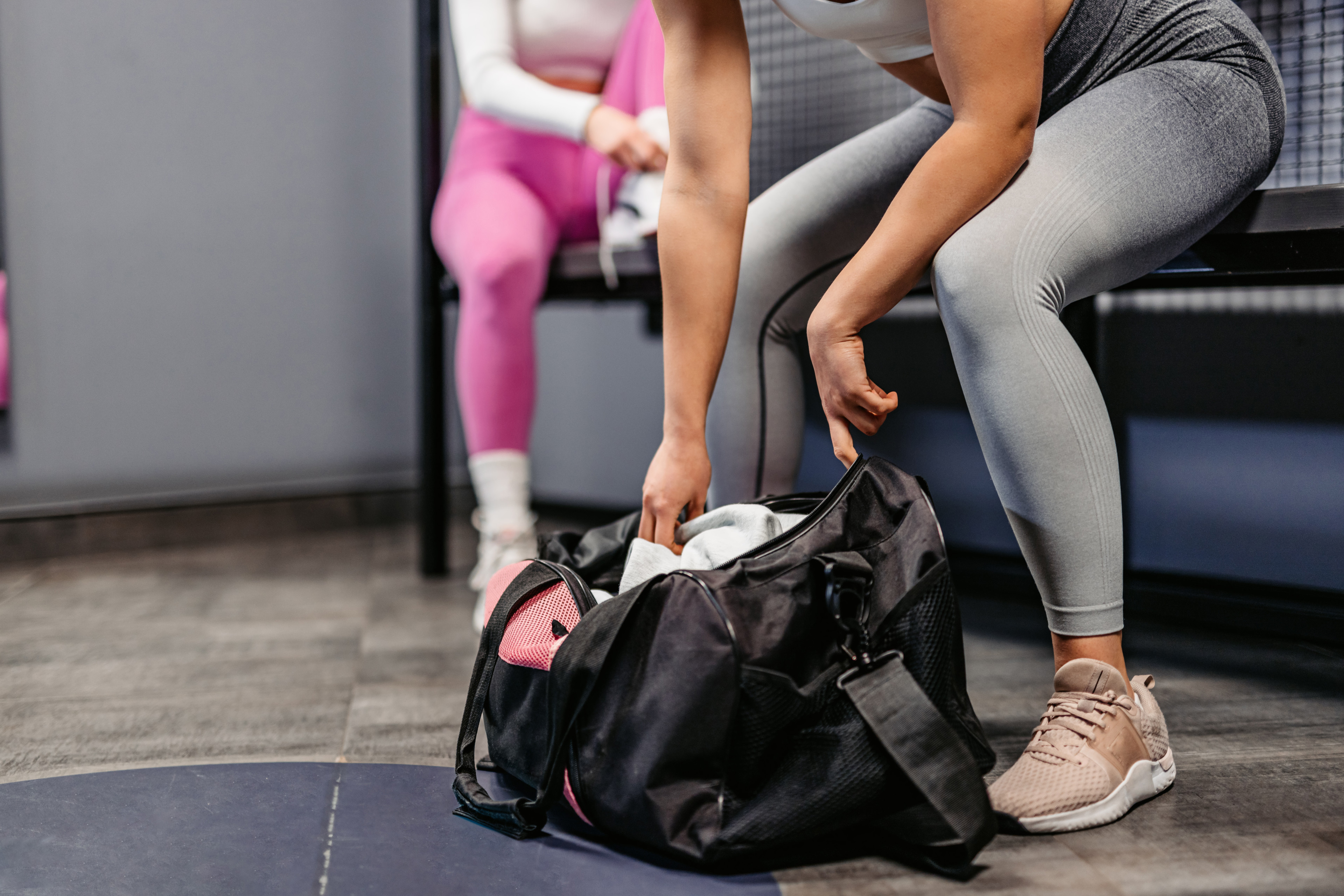 Woman opening up gym bag in a locker room 