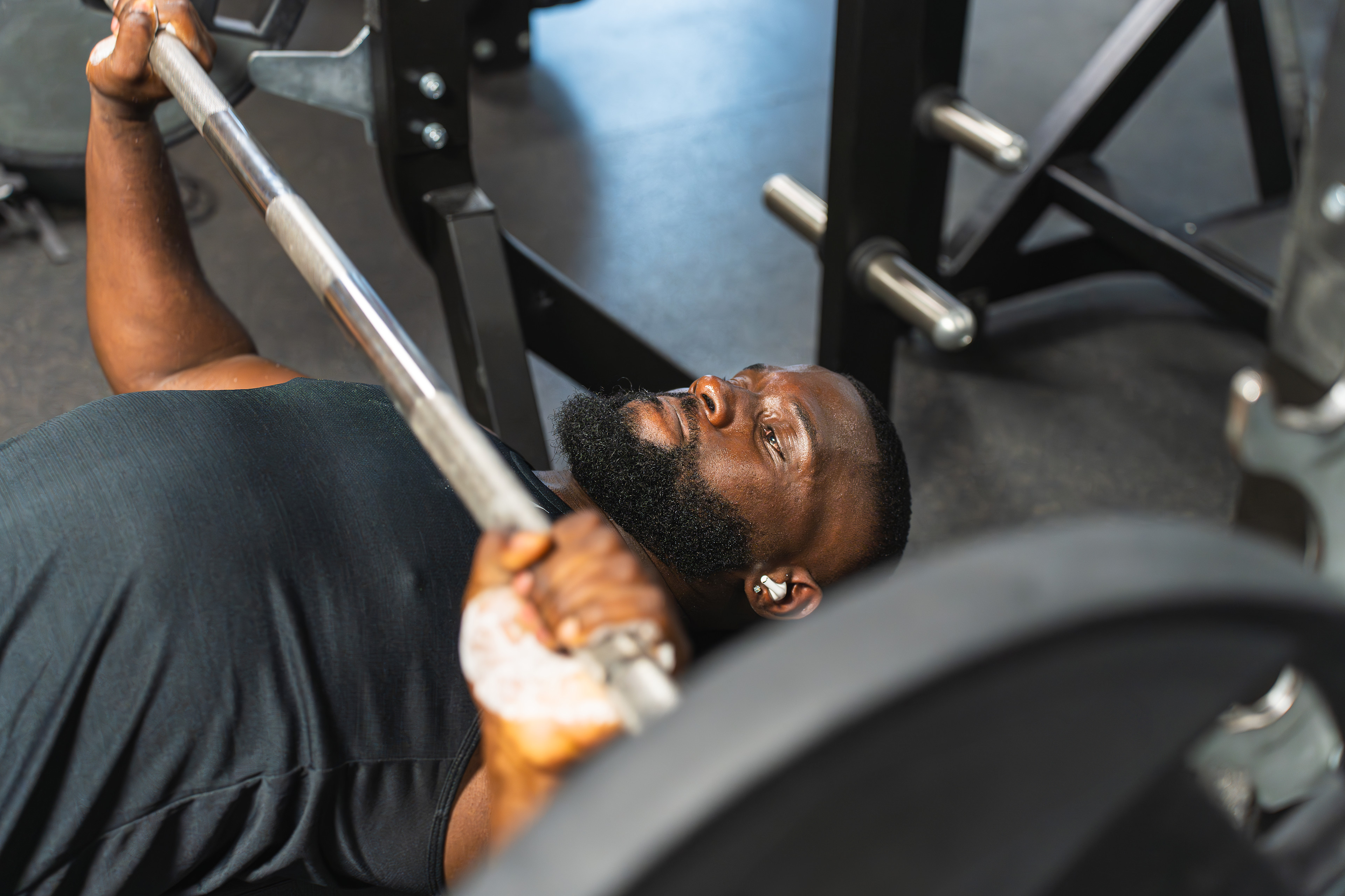 Man at the gym doing a bench press with a weighted barbell.