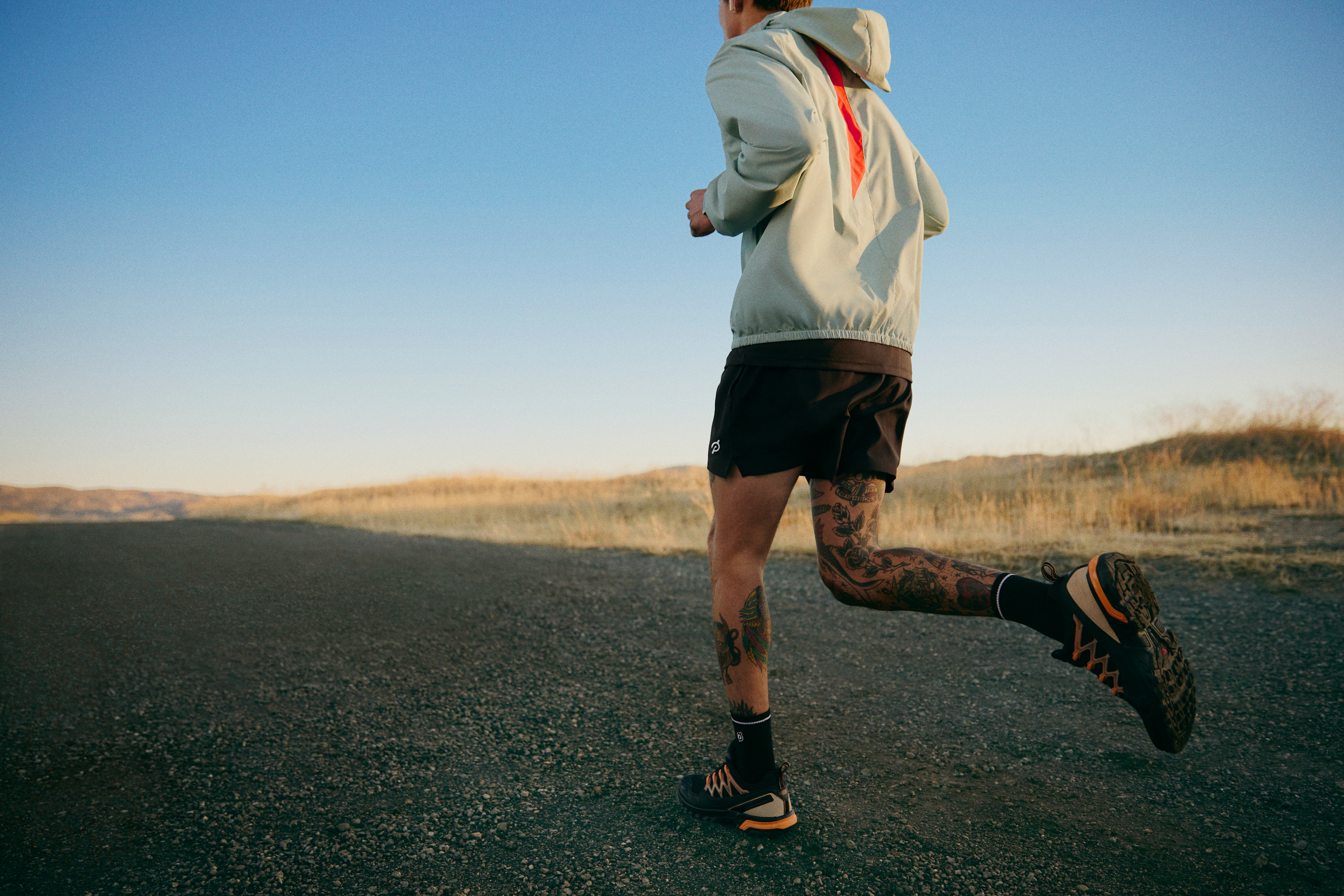 Man wondering how many miles a week he should run while running outside on a gravel road.
