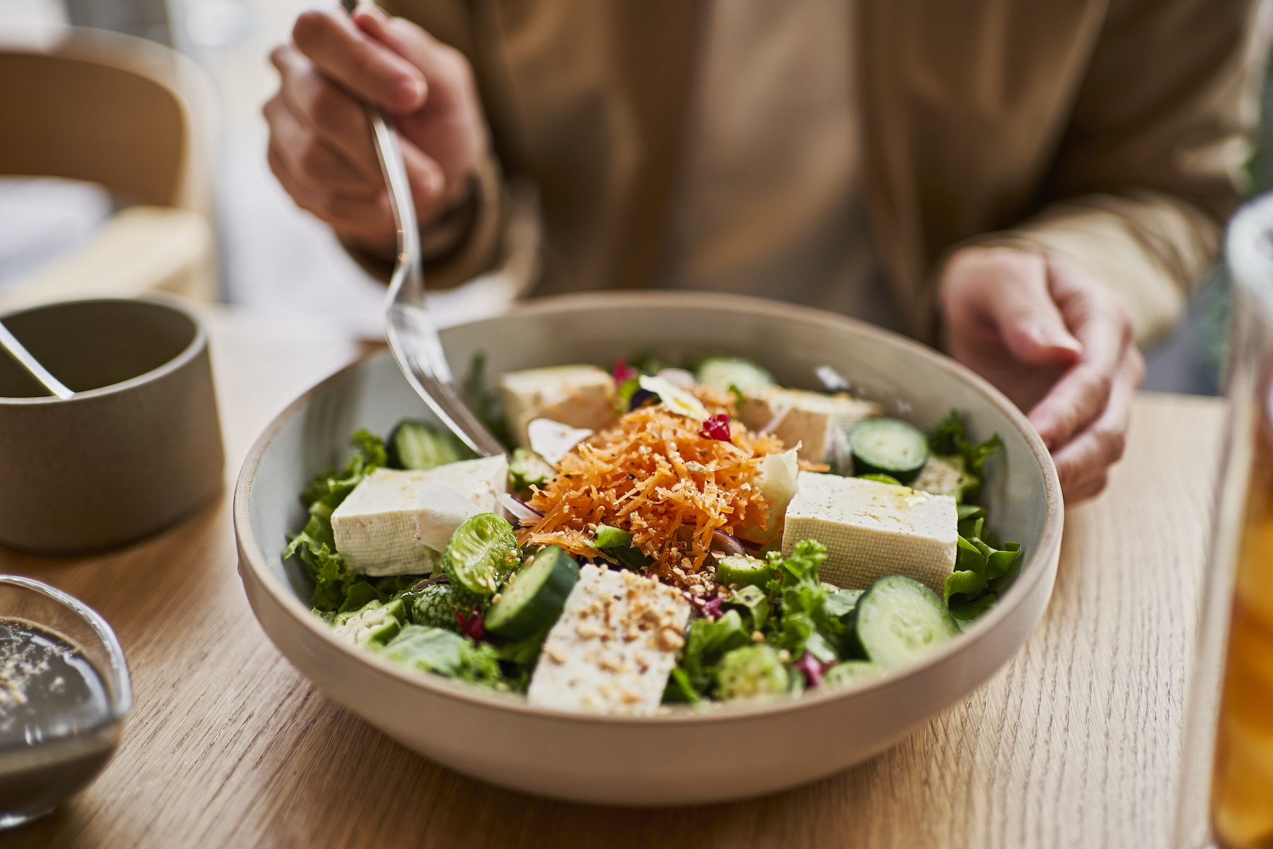 A woman enjoying a lean protein tofu bowl.