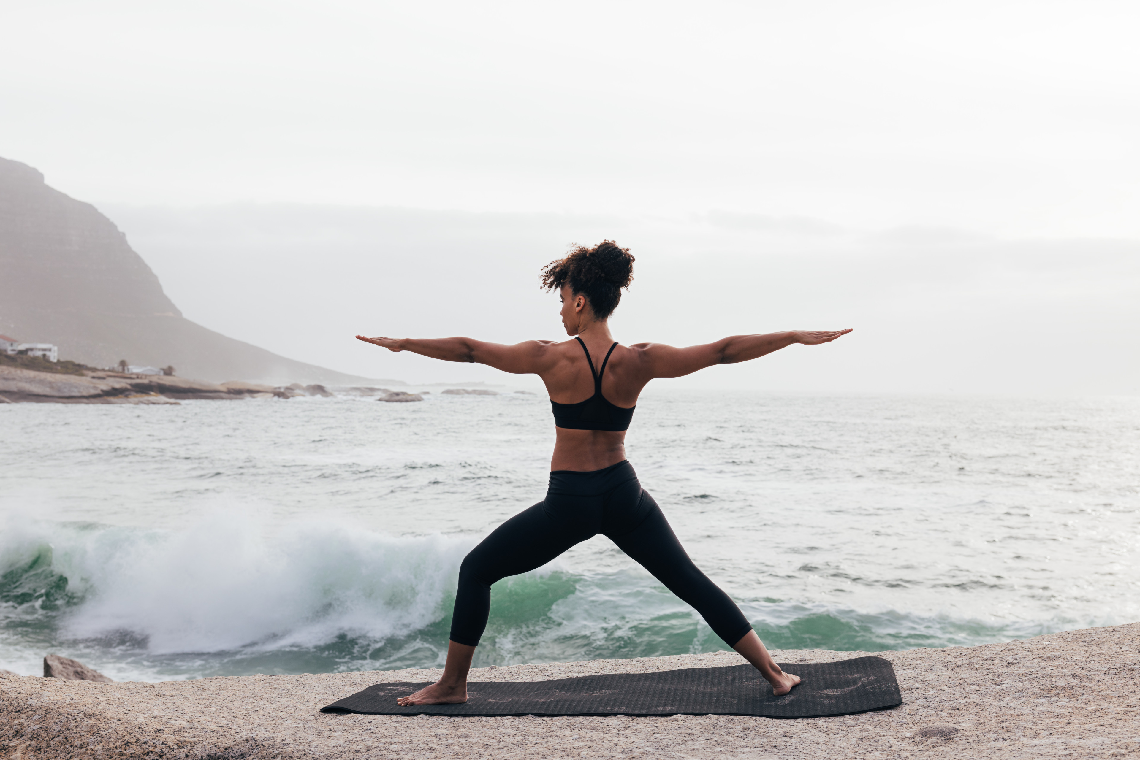 Woman doing Warrior 2 pose on beach