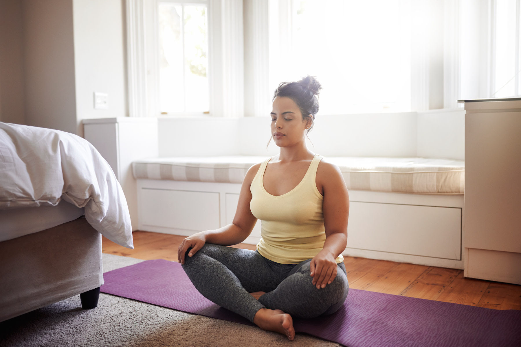 A woman sitting in her room practicing meditation before exercise.