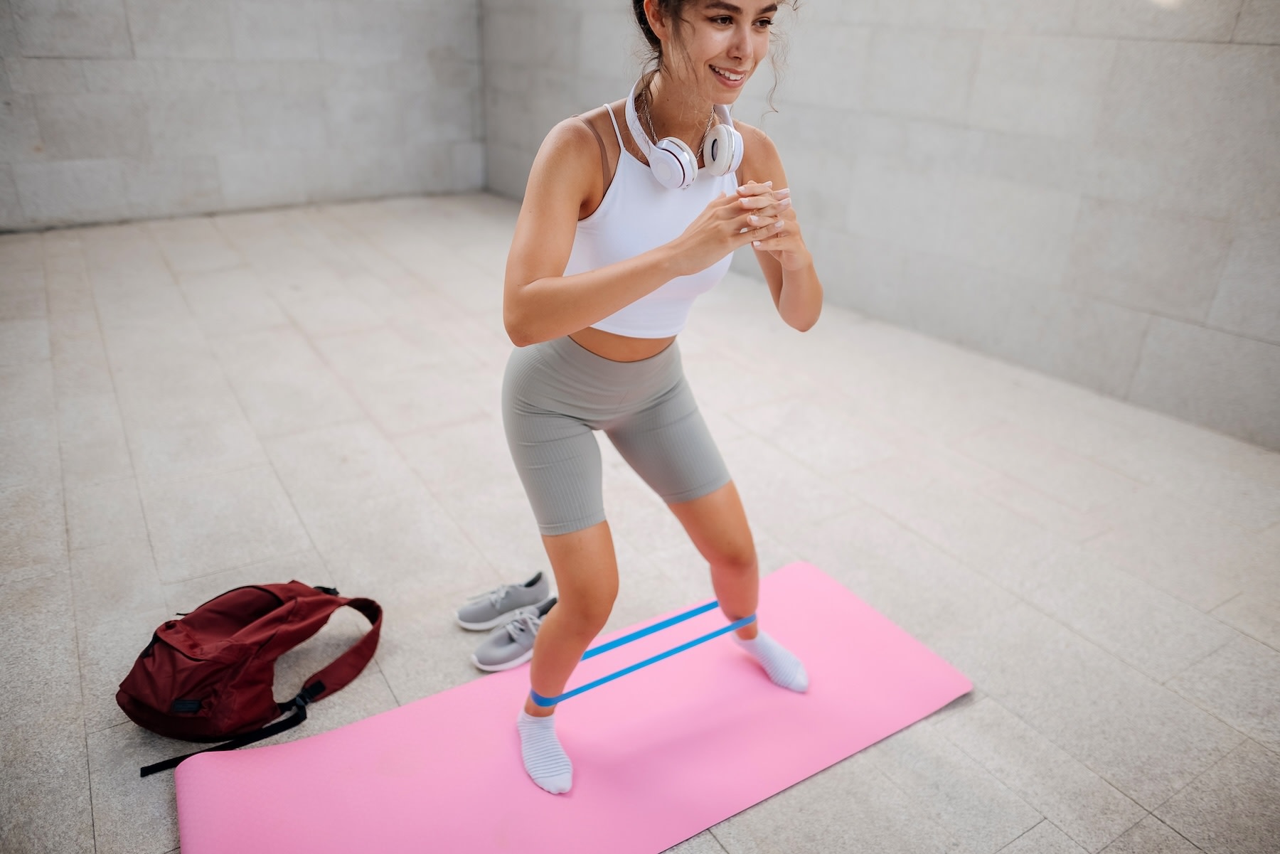 A woman working out with a resistance band, stepping from side to side, on a pink yoga mat.