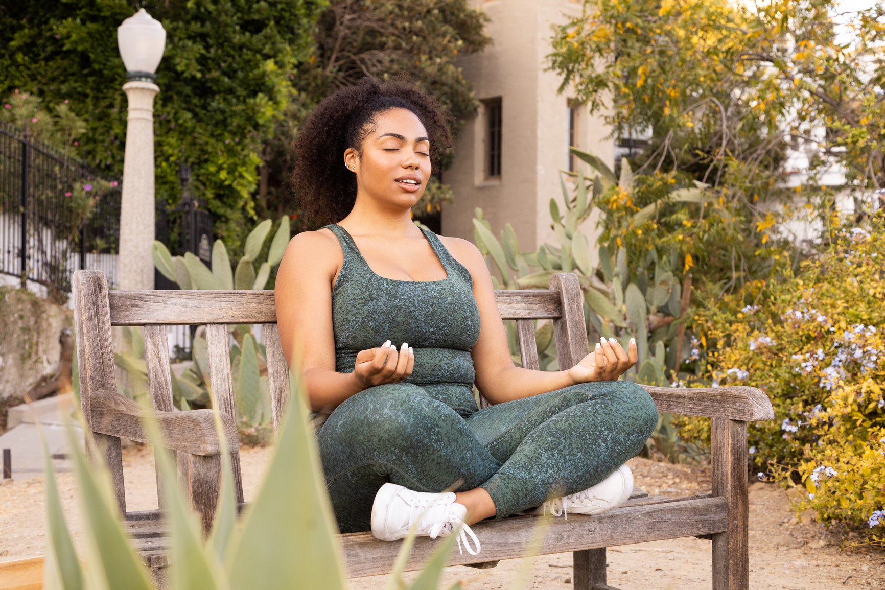 Woman meditating outside on a park bench in workout clothes