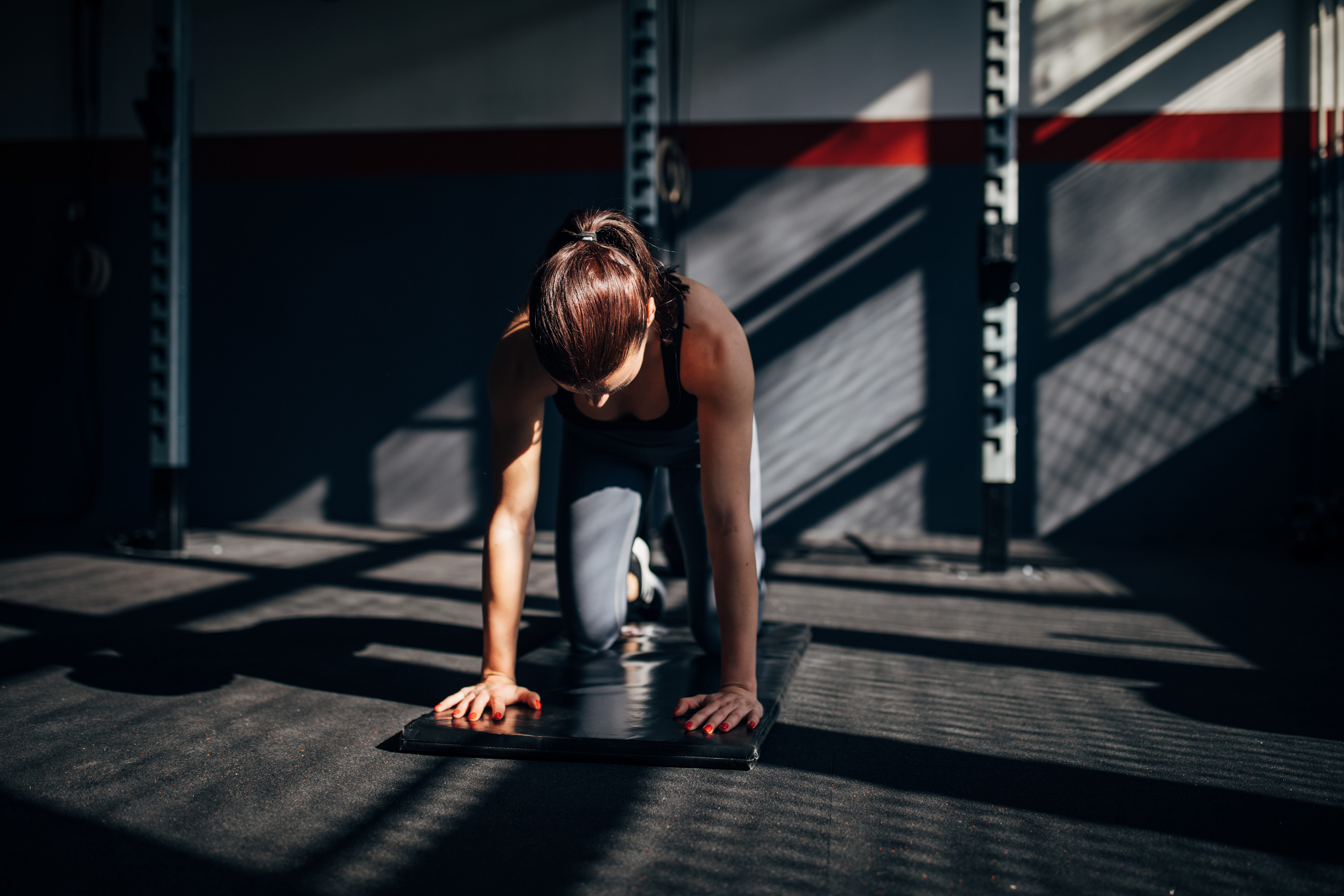 Woman preparing to do a bear plank core exercise during a workout at the gym.