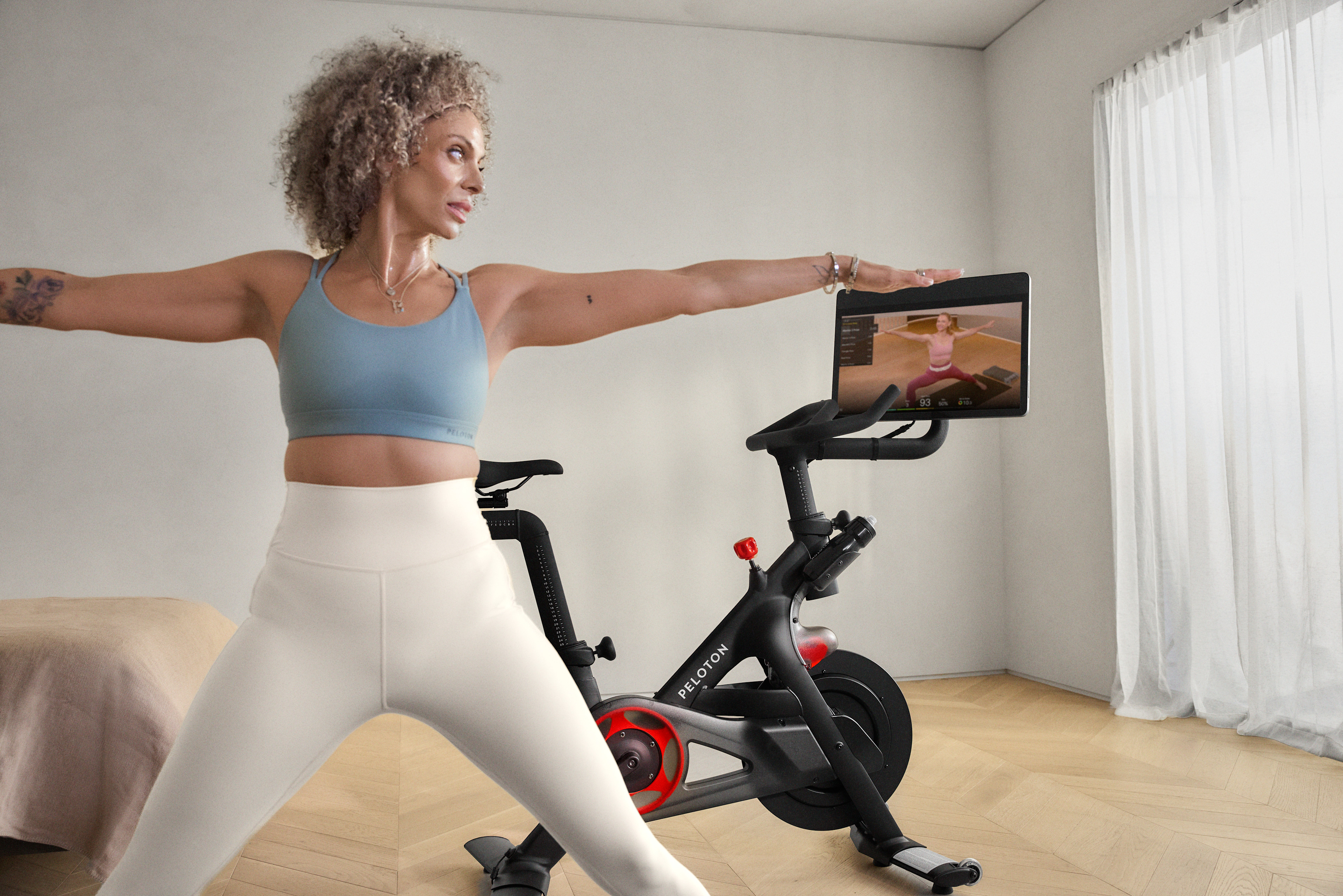 Woman doing a yoga cross training workout at home with her Peloton Bike.
