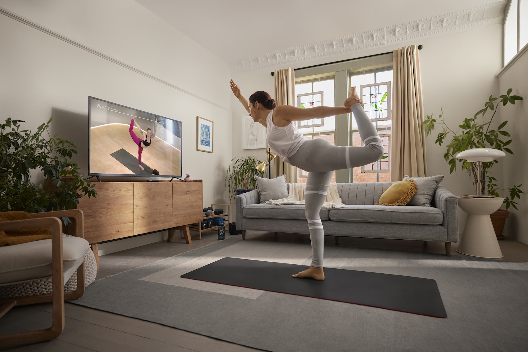 Woman practices a dancer pose at home. 