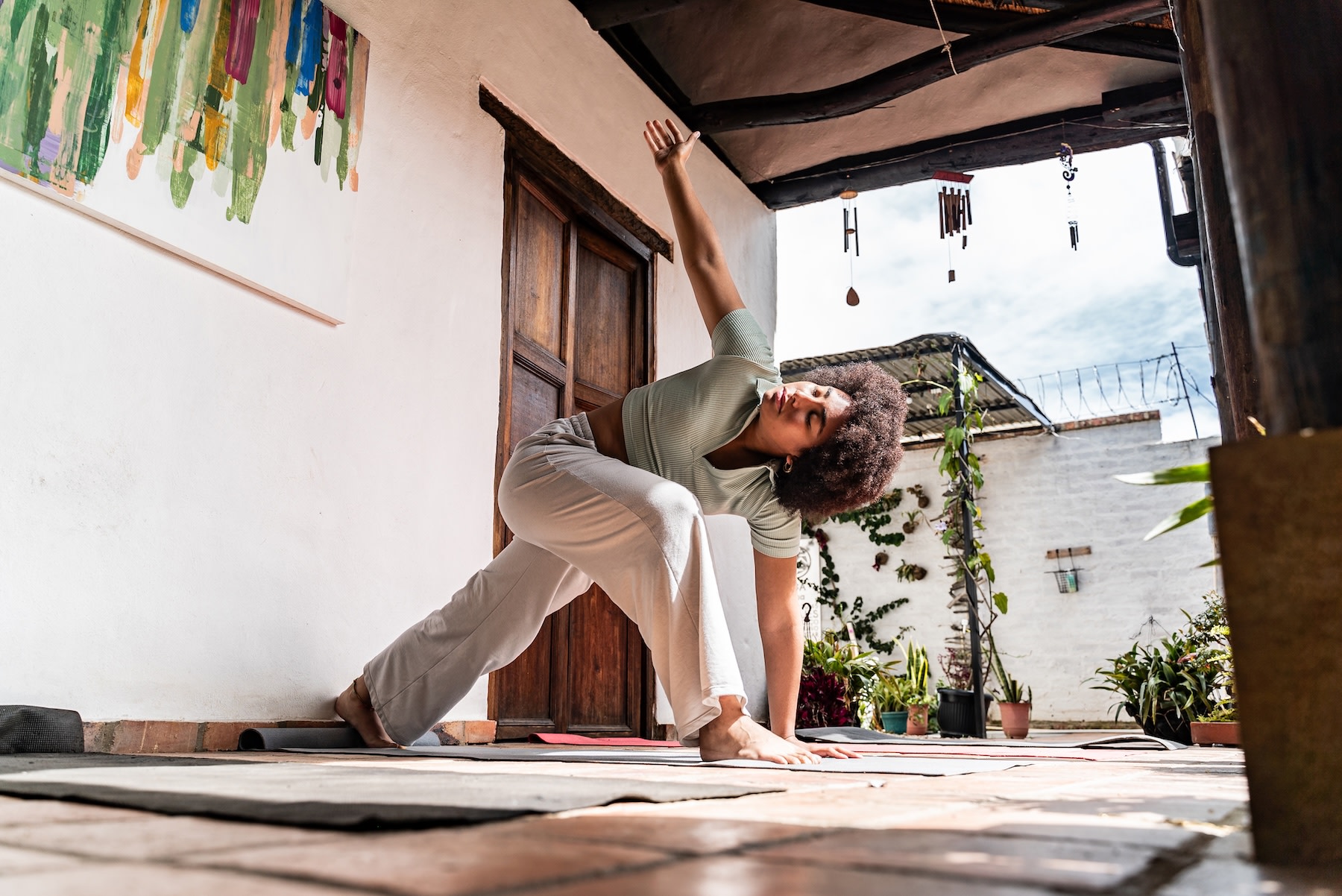 A woman doing a Runner's Lunge Twist while practicing yoga on an outdoor patio as part of her Sunday reset routine.