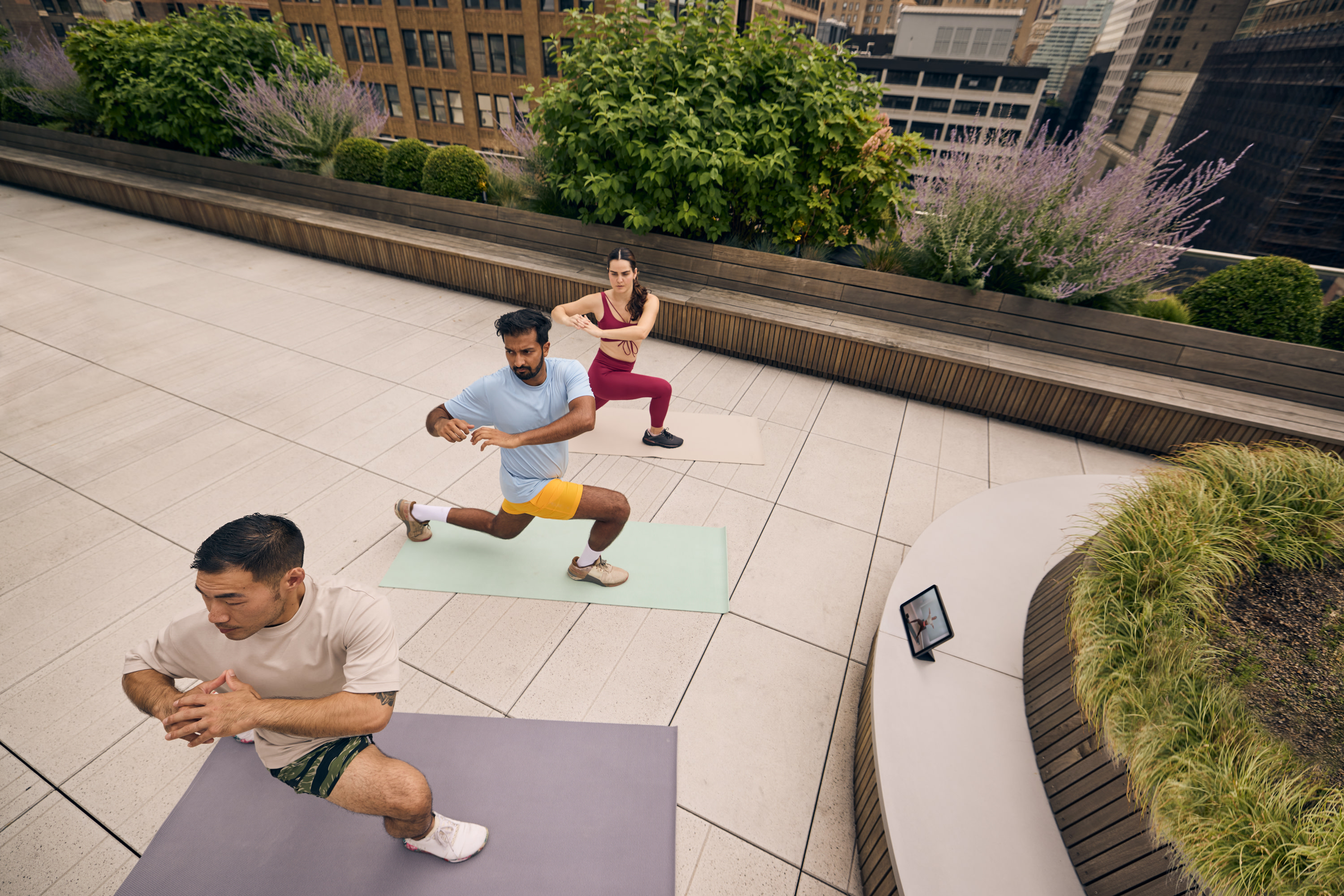 3 exercisers practicing yoga on a rooftop in the city