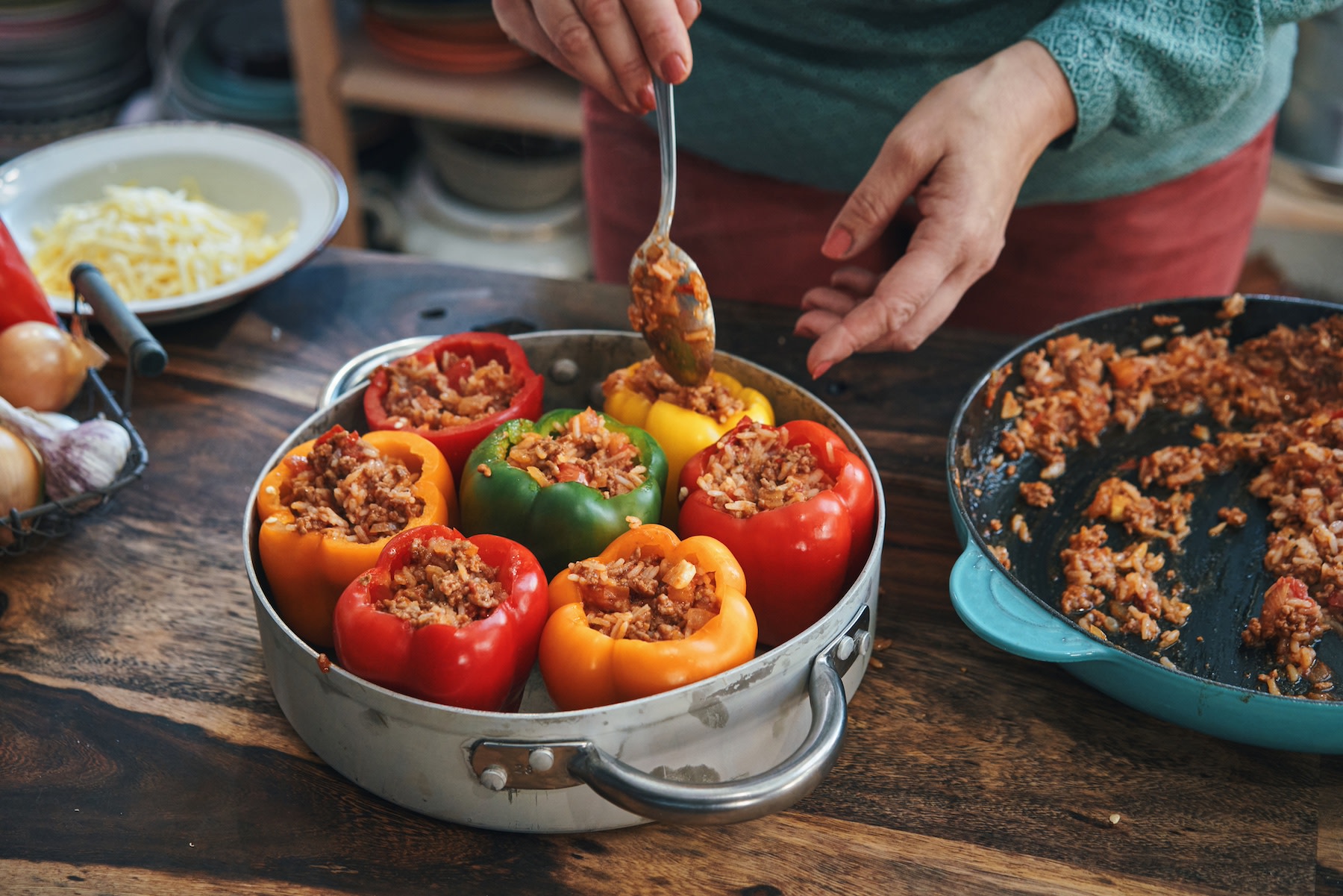 A woman stuffing bell peppers with ground beef, a lean protein.