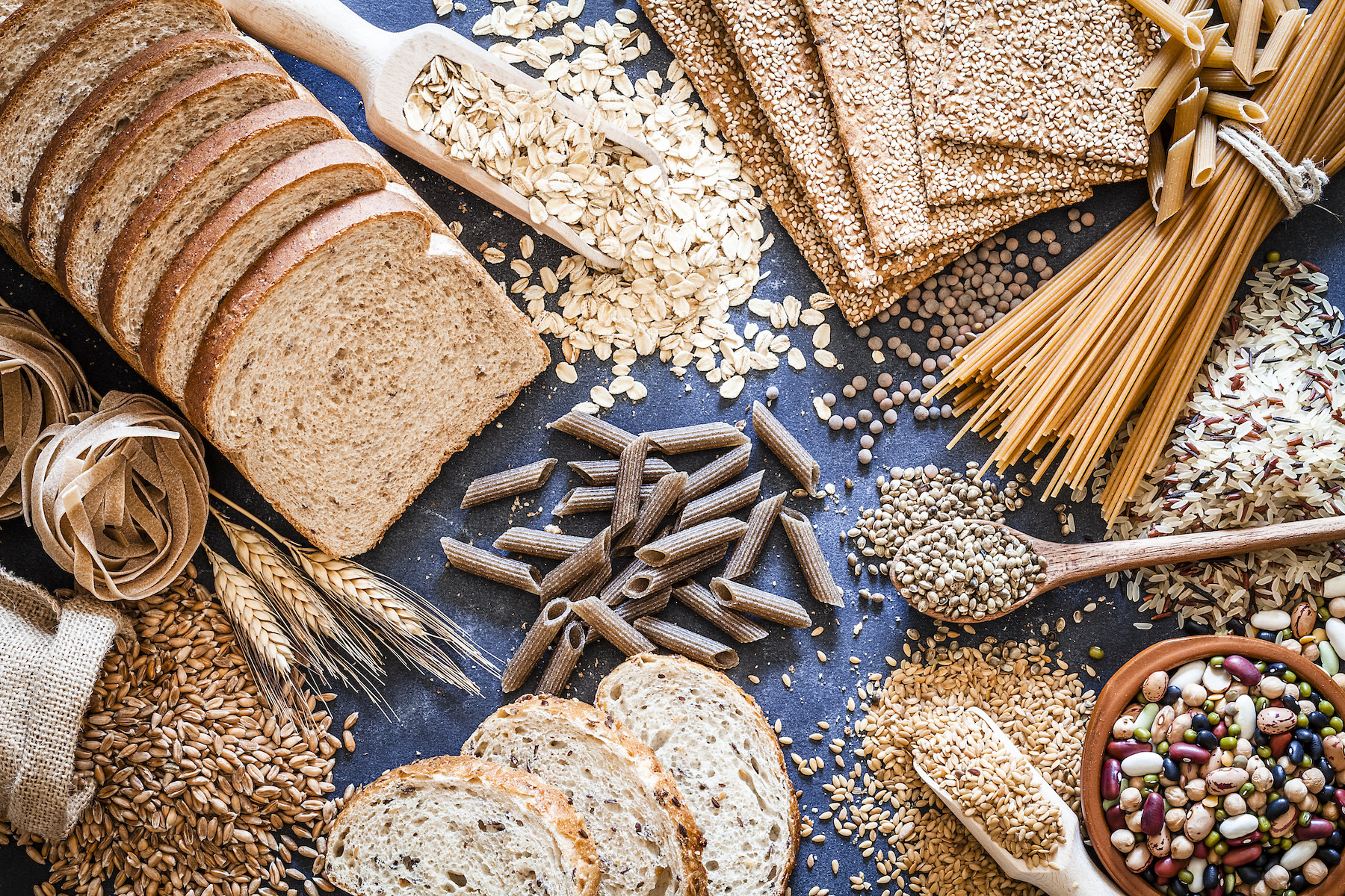 A flay-lay of healthy carbohydrate food sources like whole-grain bread and pasta.