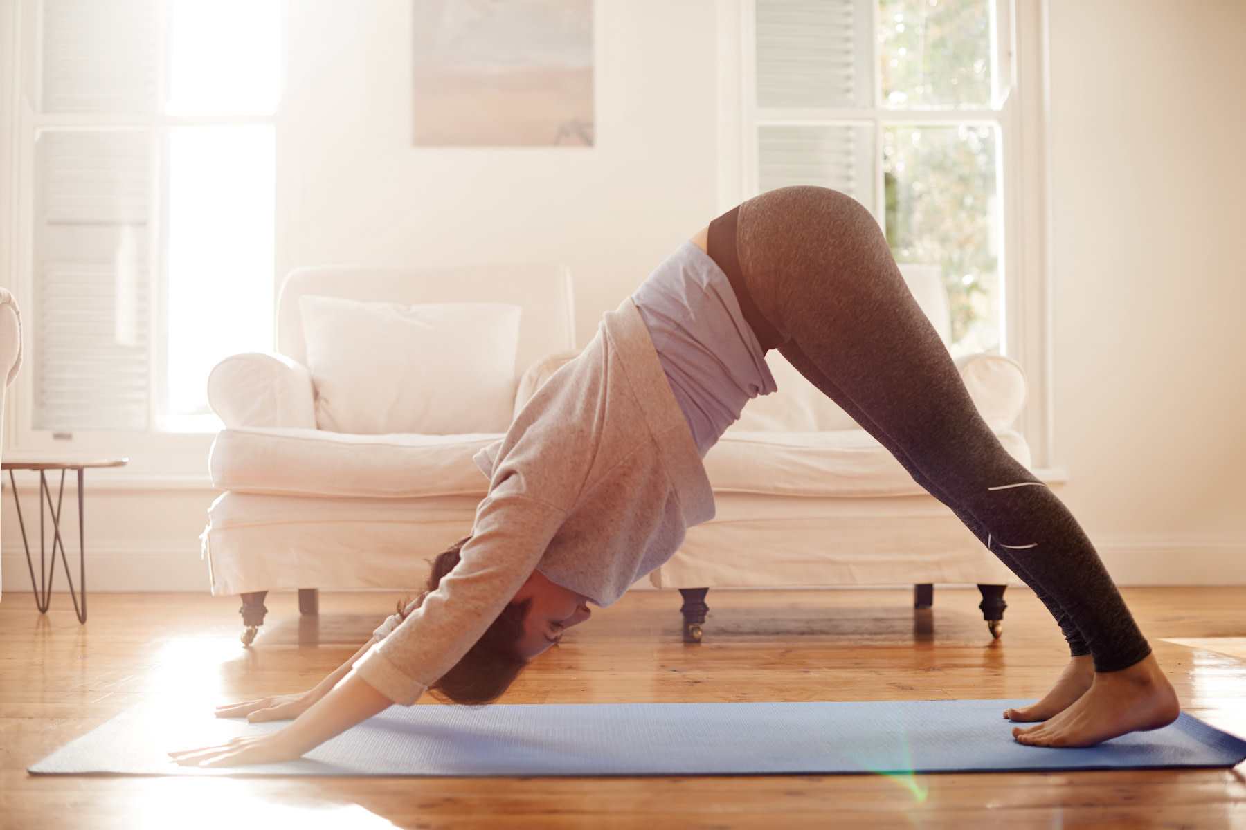 Woman practices Downward-Facing Dog Pose in her house