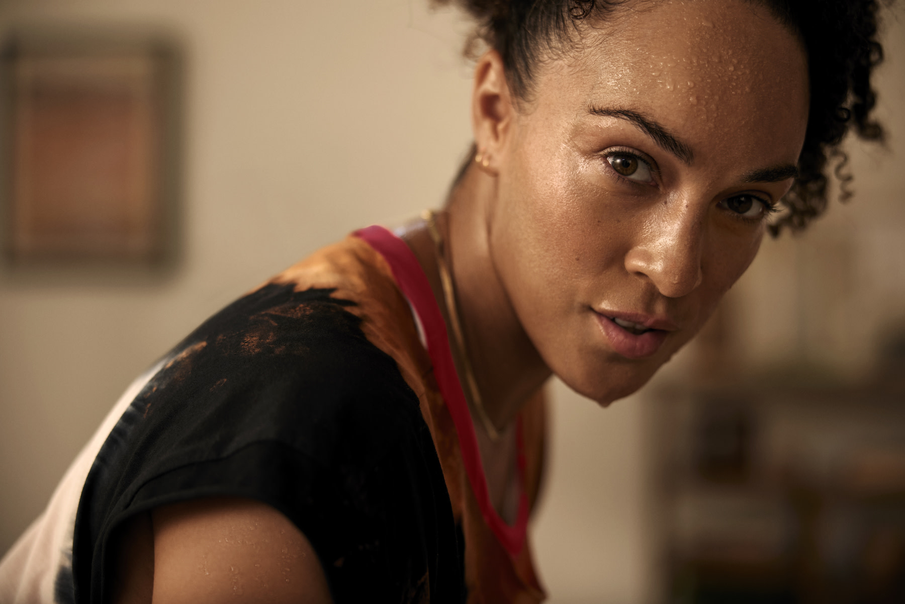 In this image for an article about high-performance mindsets, a woman is looking powerfully into the camera. She's sweaty and has her hair up.