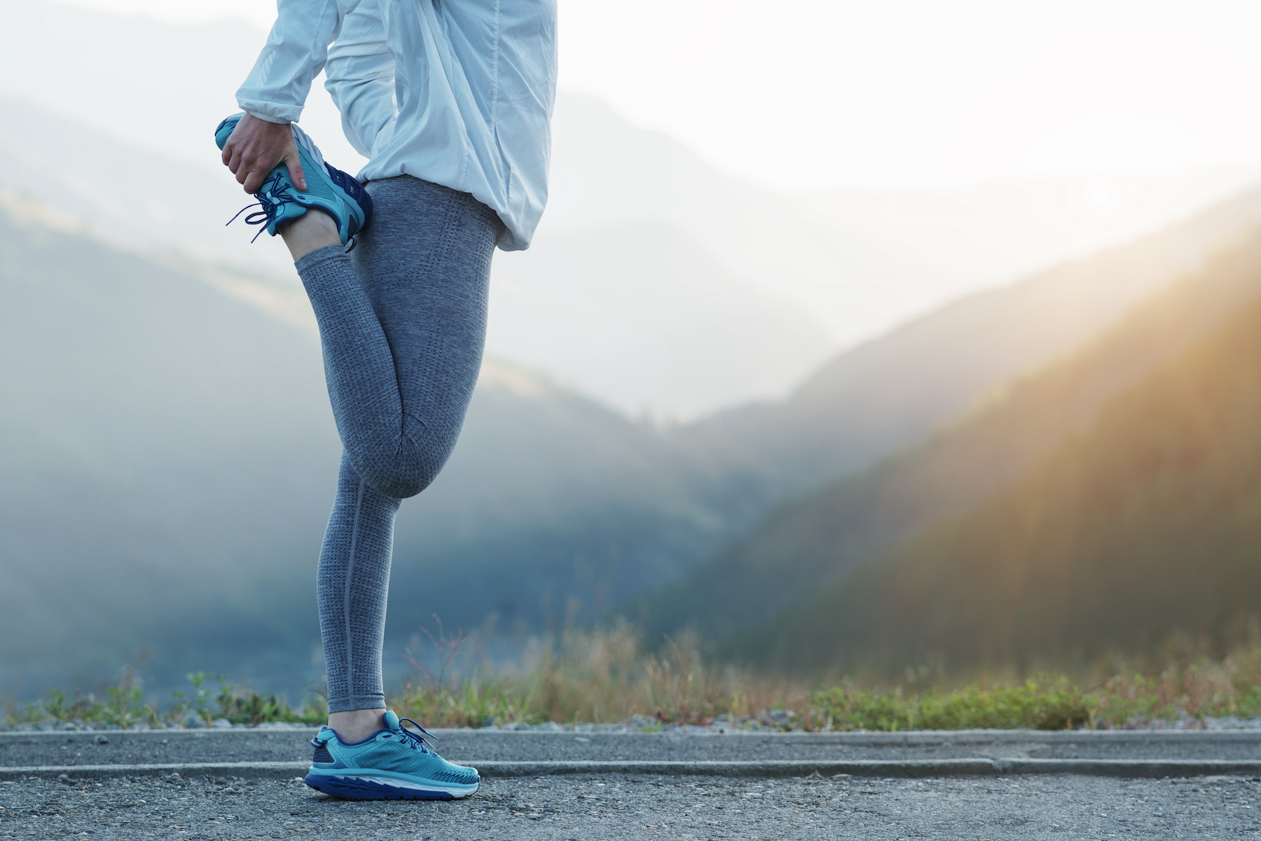 Woman does a standing quad stretch, an IT band stretch