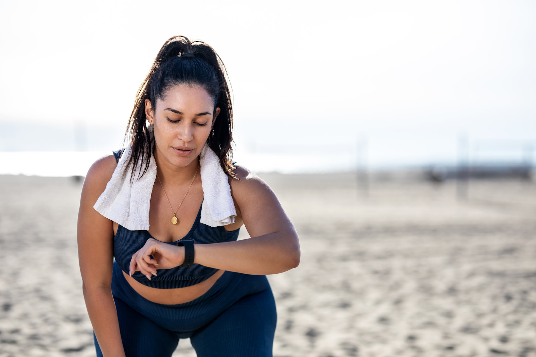 A woman checking her heart rate variability on her smartwatch while at the beach.