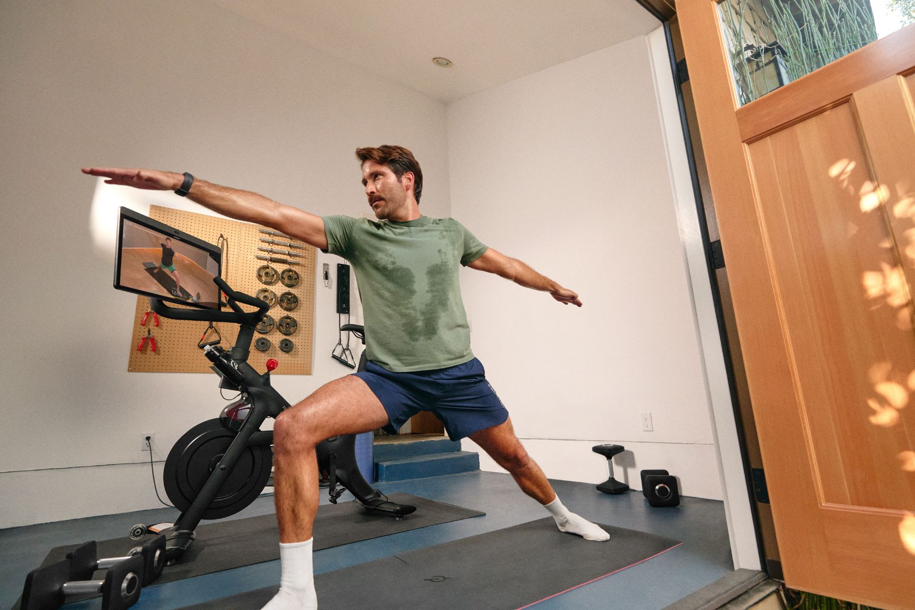 Man exercising next to a Peloton Bike+