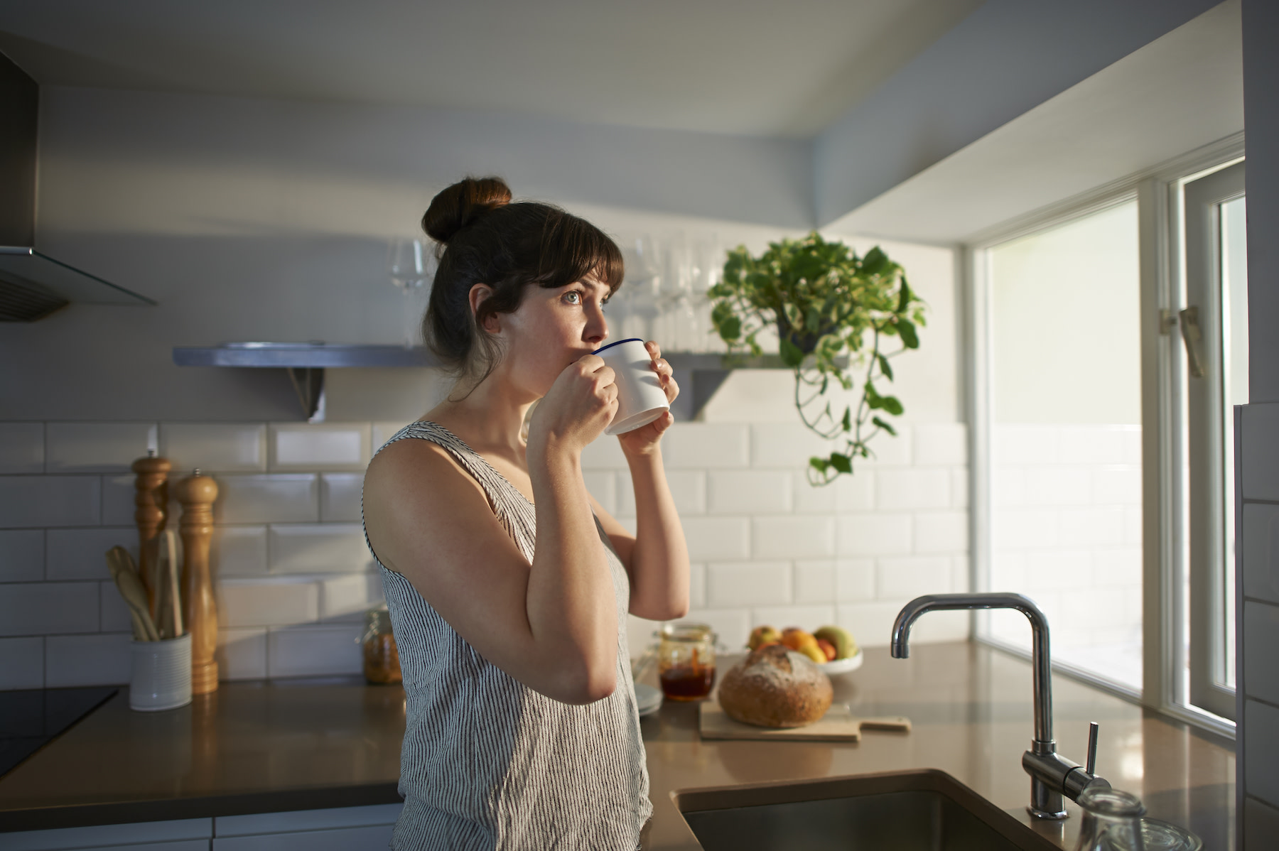 A woman in her kitchen drinking coffee before a workout.