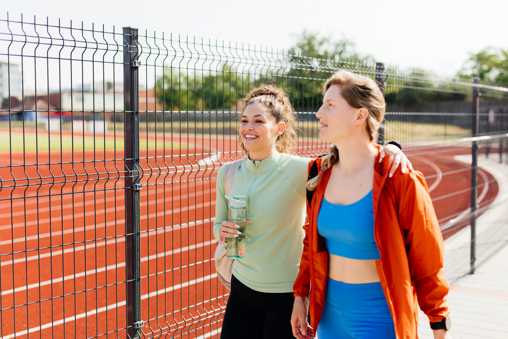 Two women walking side by side by track