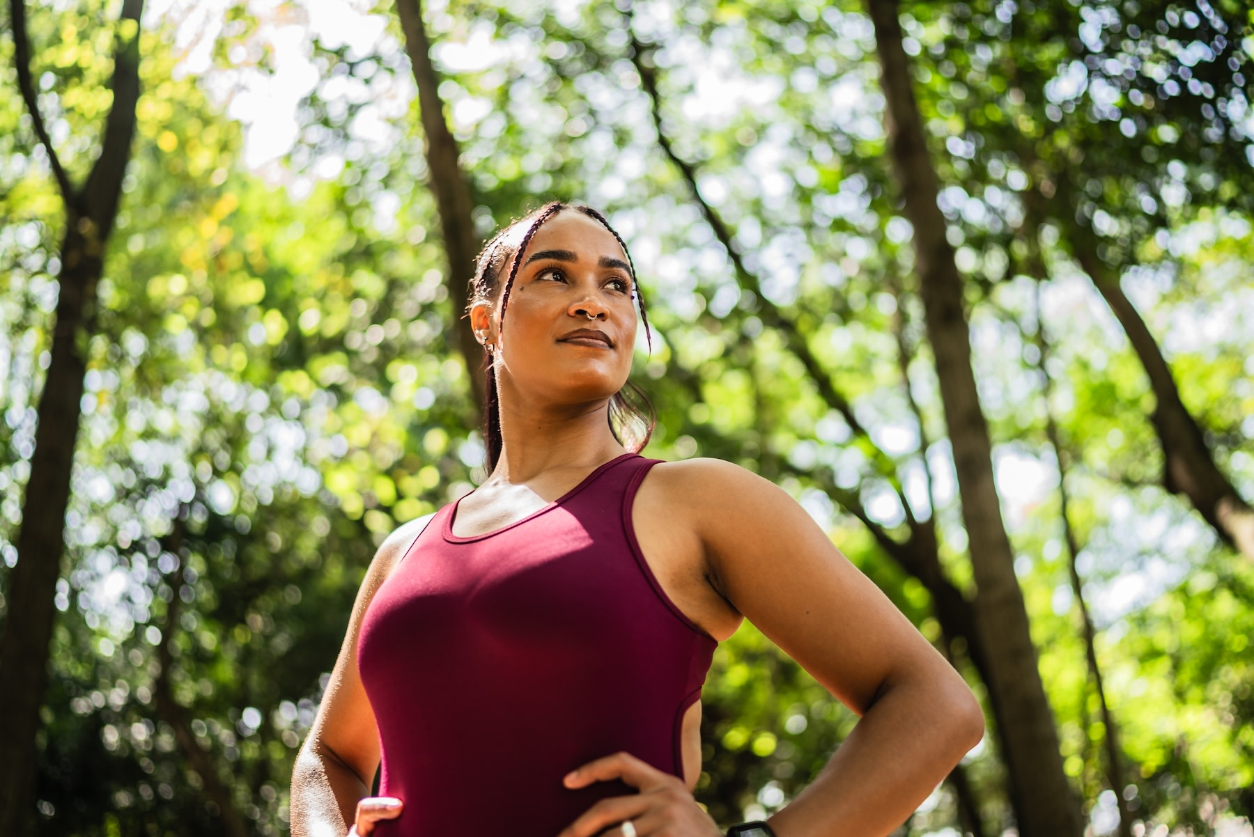 A woman with her hands on her hips, doing an outdoor workout in a park. She is feeling strong and confident.