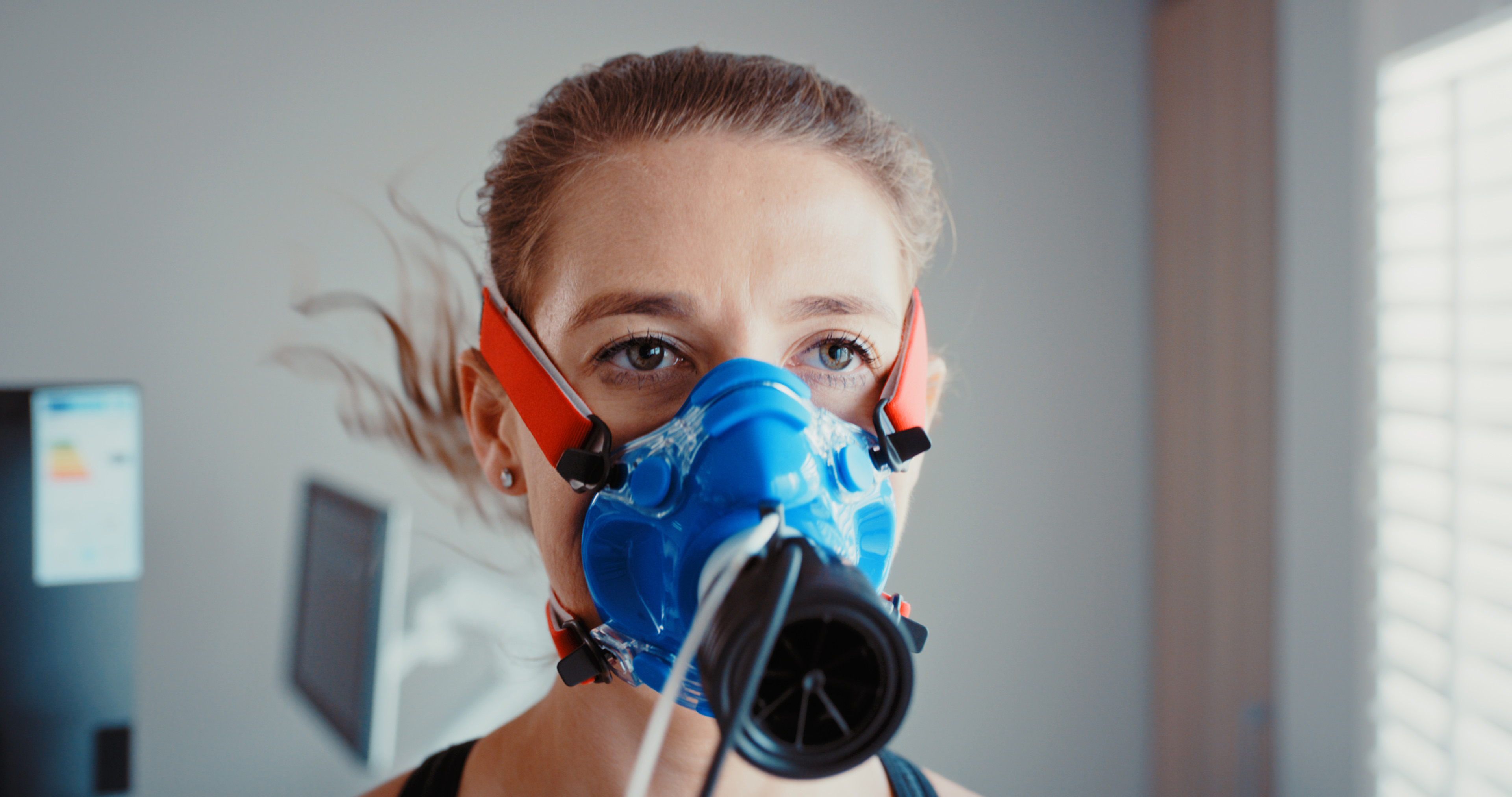 Woman running on a treadmill with a mask to measure running economy