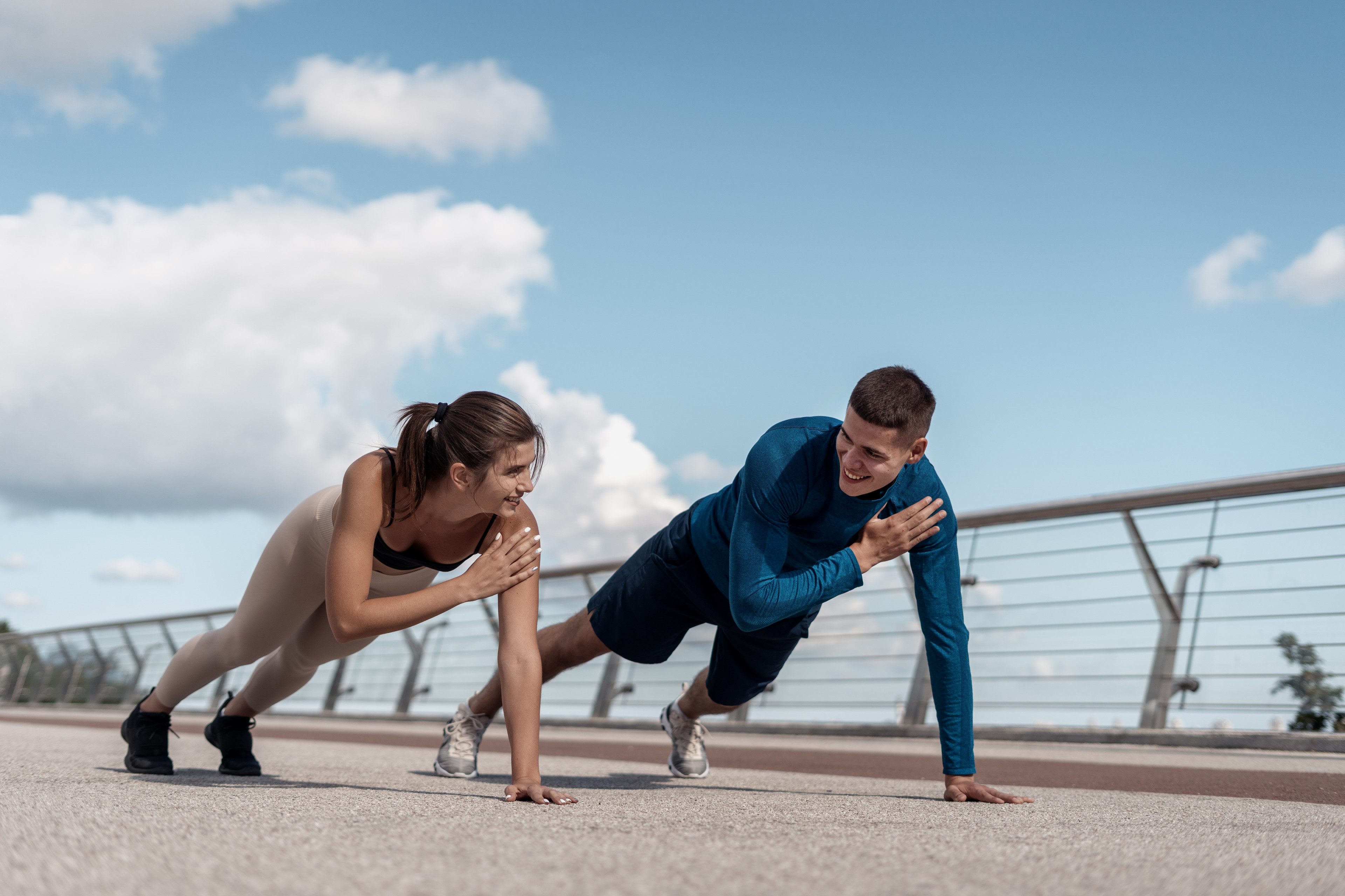 Woman and man do shoulder taps exercise outdoors