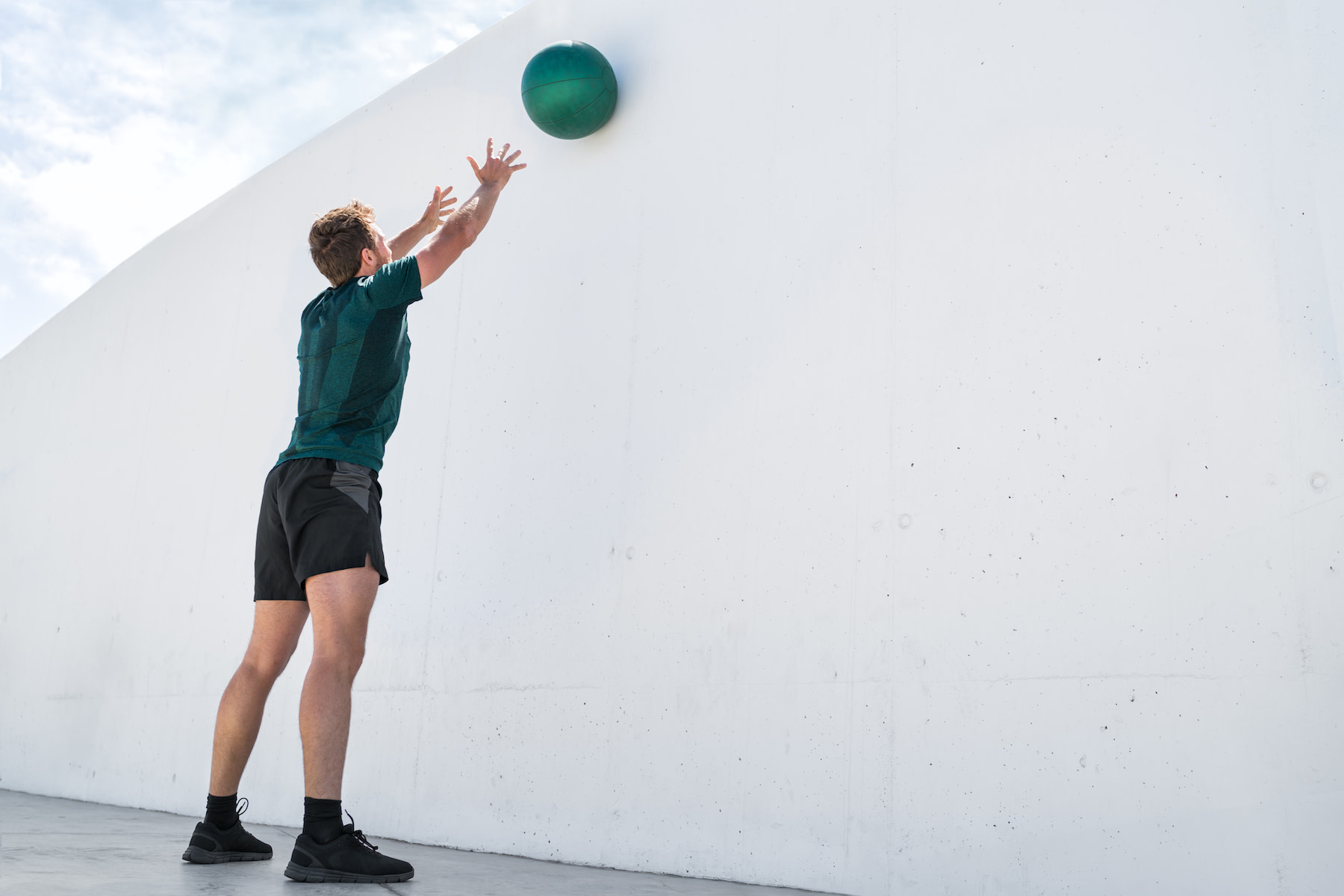 Man throws medicine ball against a wall, a plyometric exercise