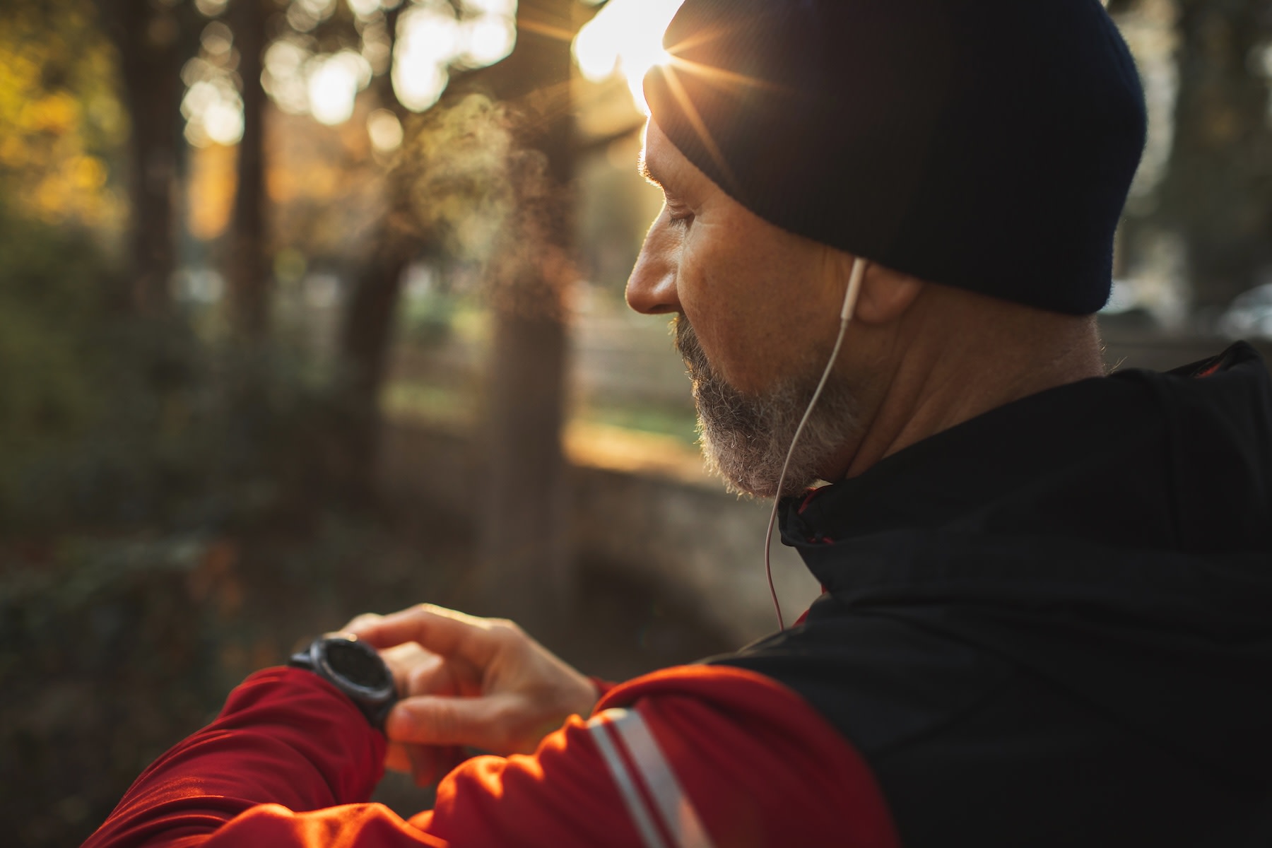 A man looking at his fitness watch before exercising outside in the morning to ease seasonal affective disorder symptoms.