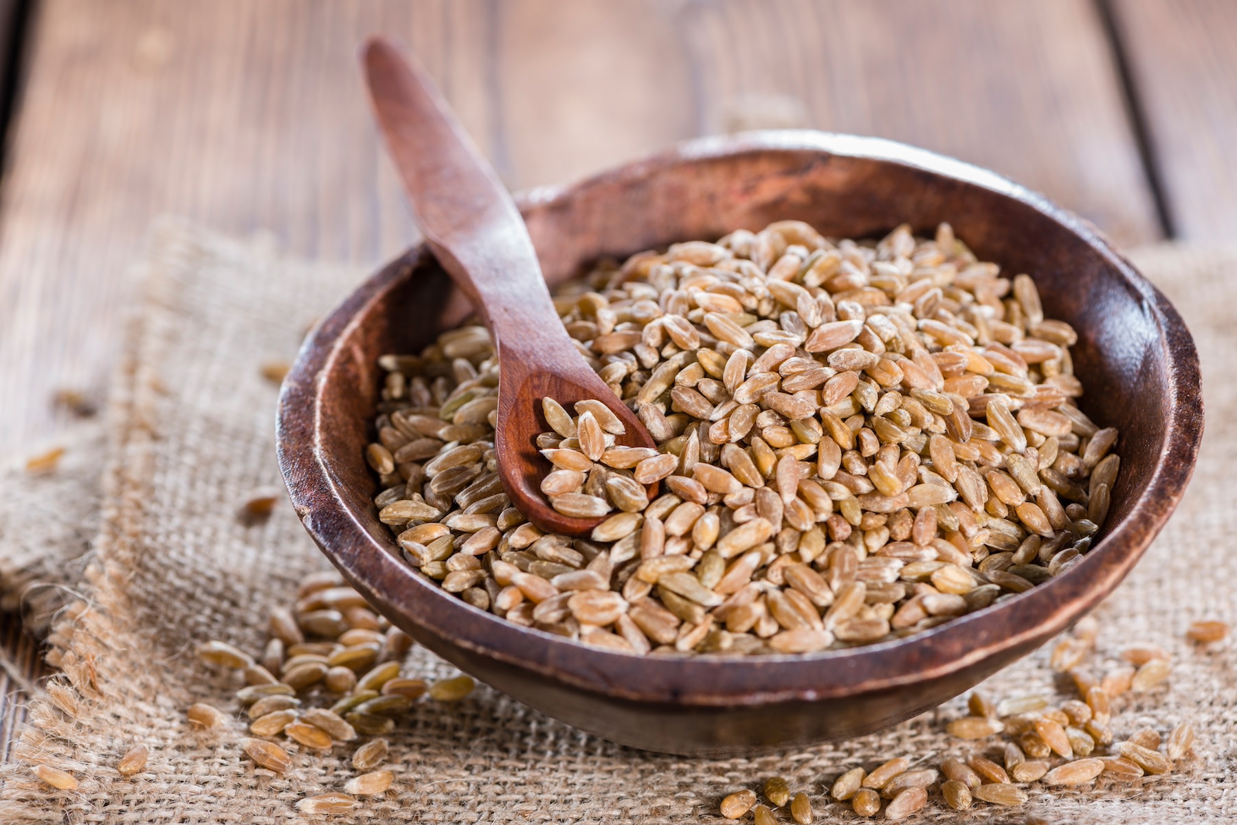 A bowl of spelt with a wooden spoon.