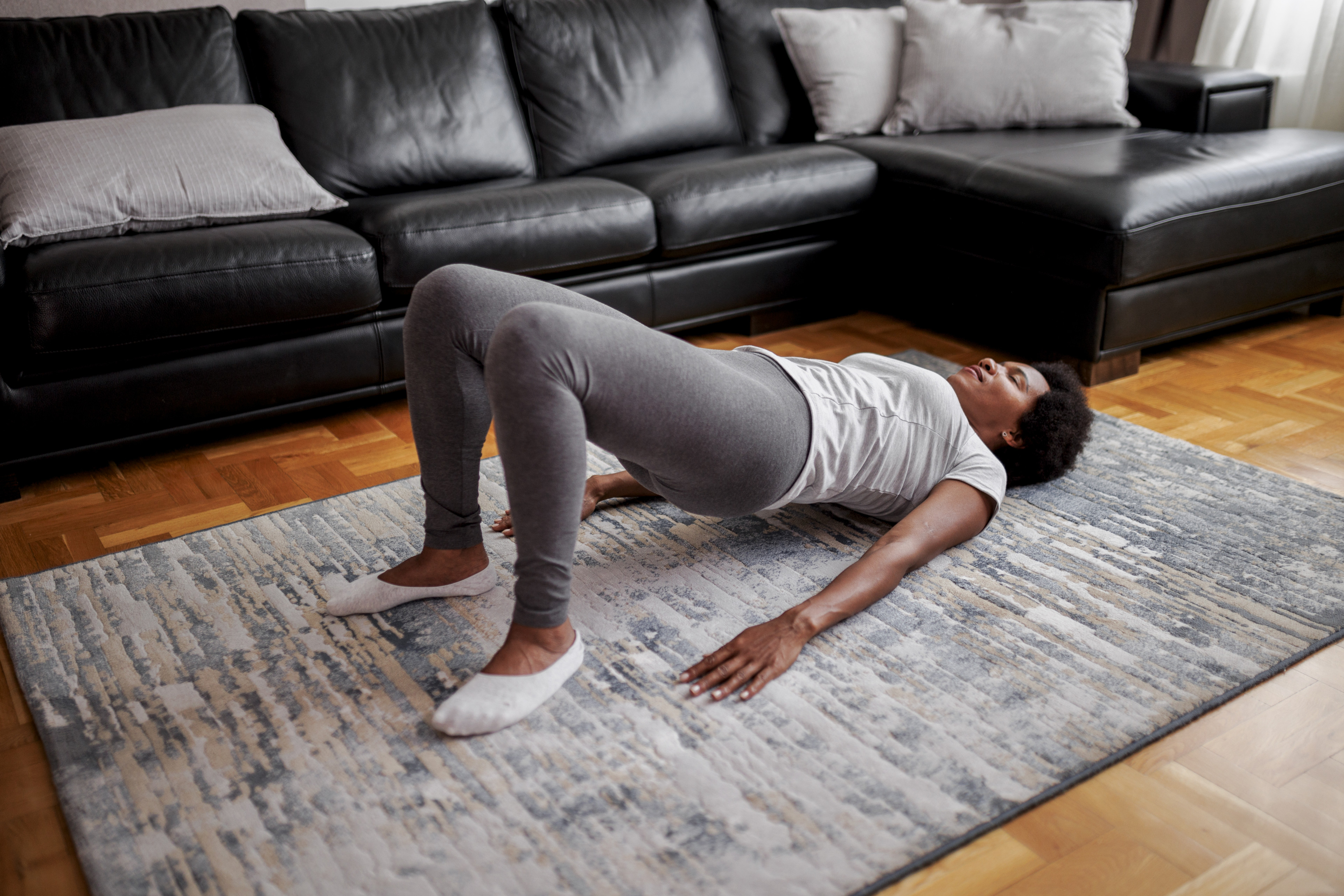 Woman at home practices glute bridge exercise 