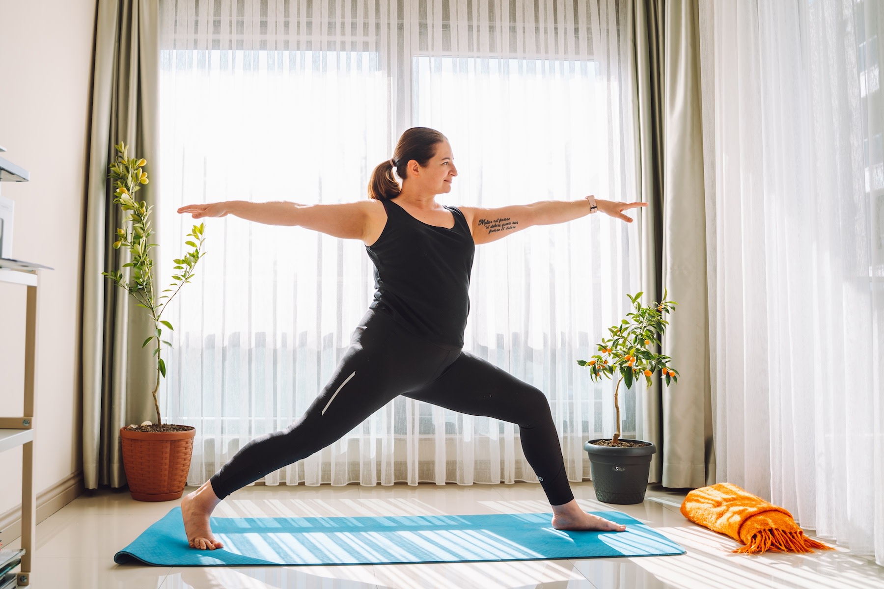 A woman in warrior pose doing yoga at home as part of her habit loop.