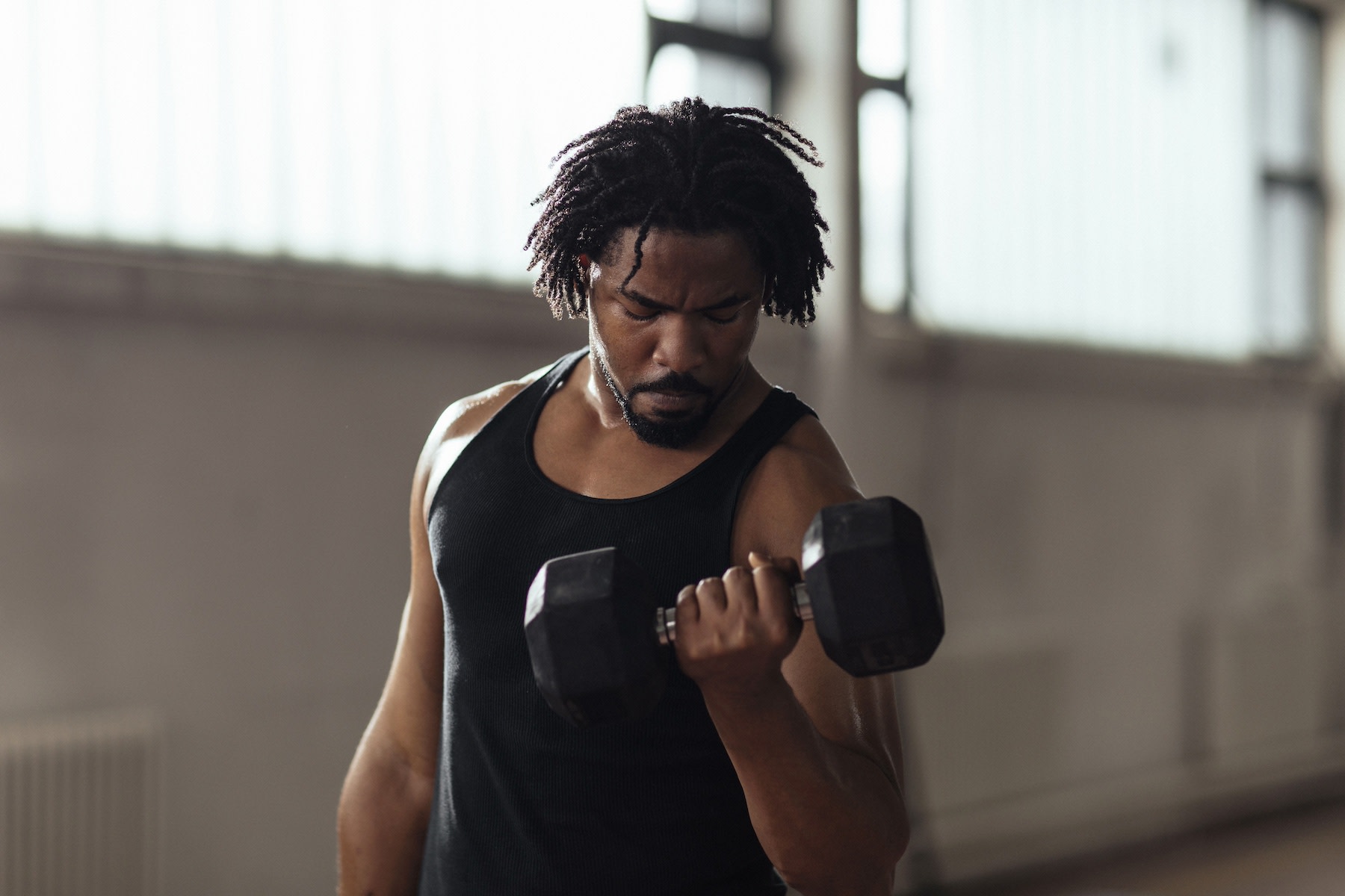 A man lifting dumbbells in a modern gym to build muscle.