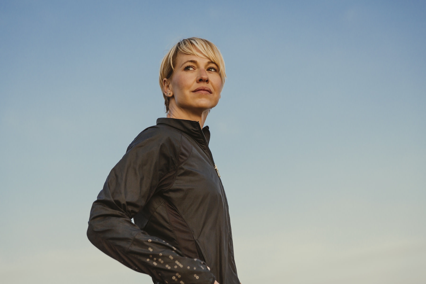 A woman looking self-confident as she stares over her shoulder while standing outside.