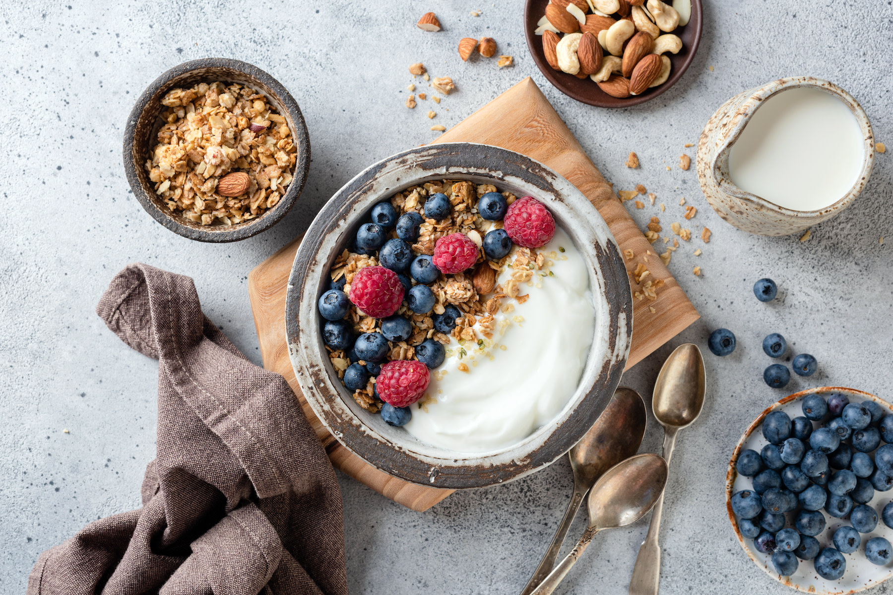 A bowl of yogurt, berries, and granola with an aesthetically pleasing table setting. Yogurt and berries are great foods for gut health. Learn more about what gut health is in this article.