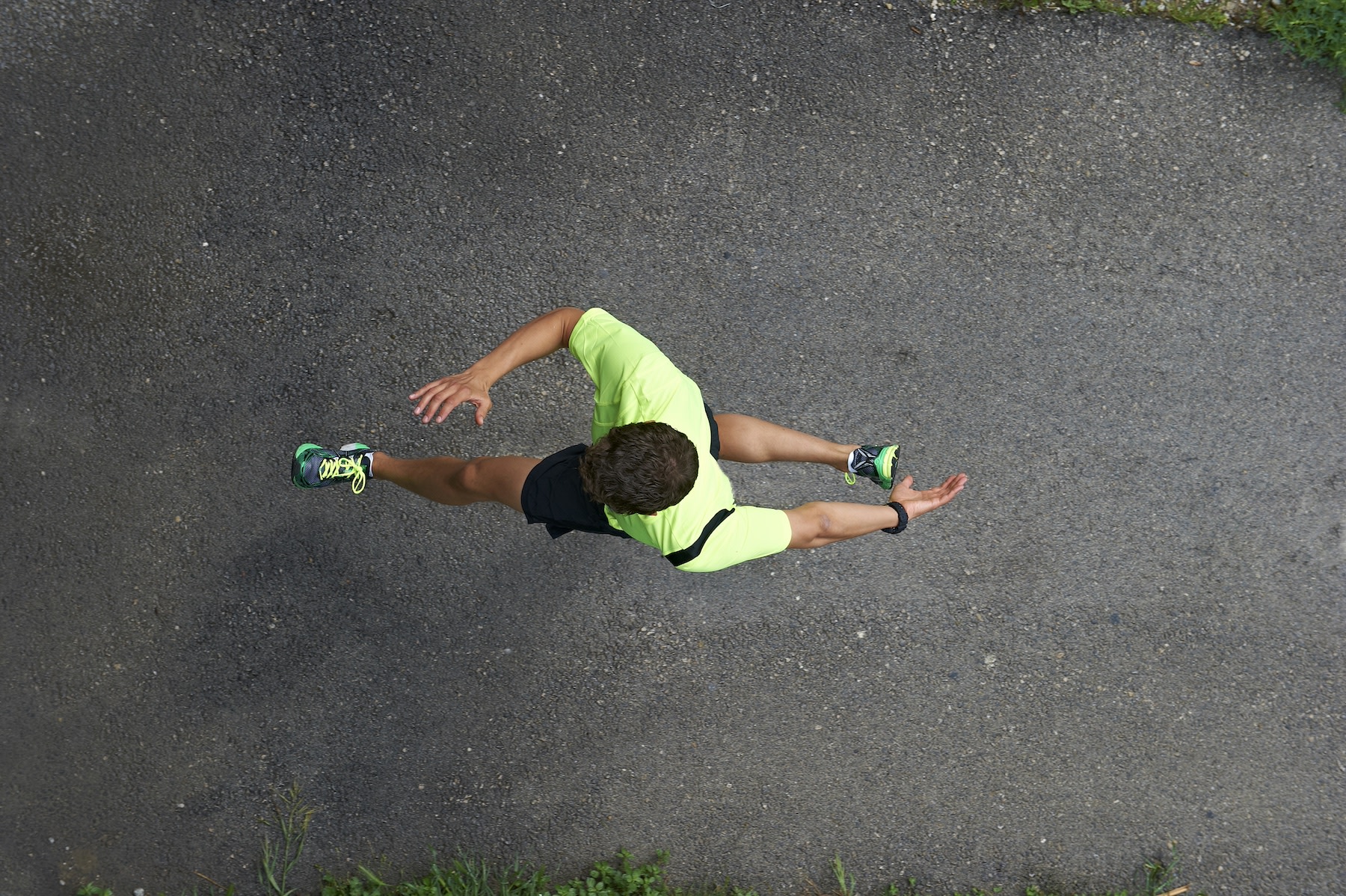 A bird's-eye view of a man sprinting on an outdoor road to practice lactate threshold training.